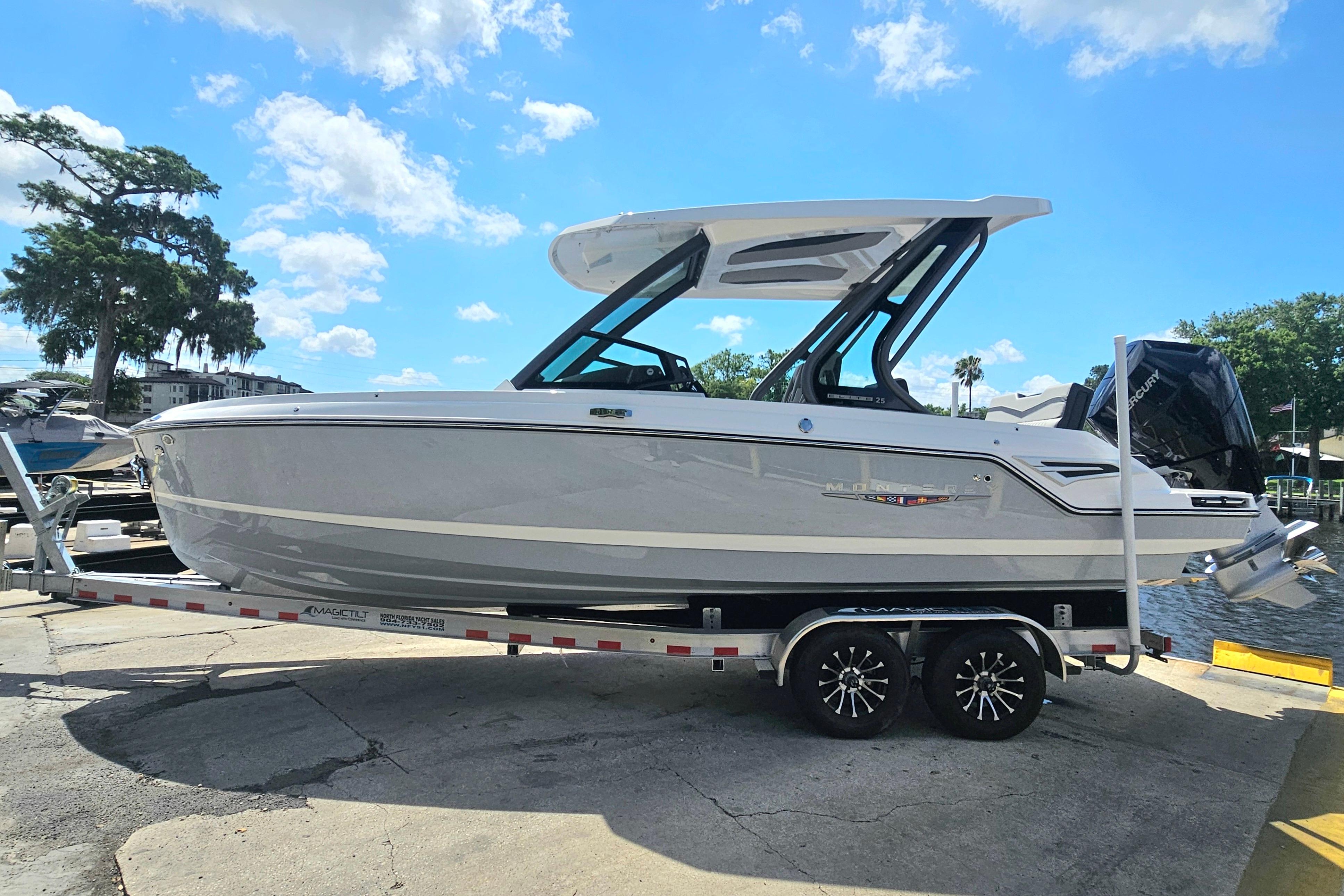 2026 Monterey Elite 25 OB boat on trailer under blue sky.