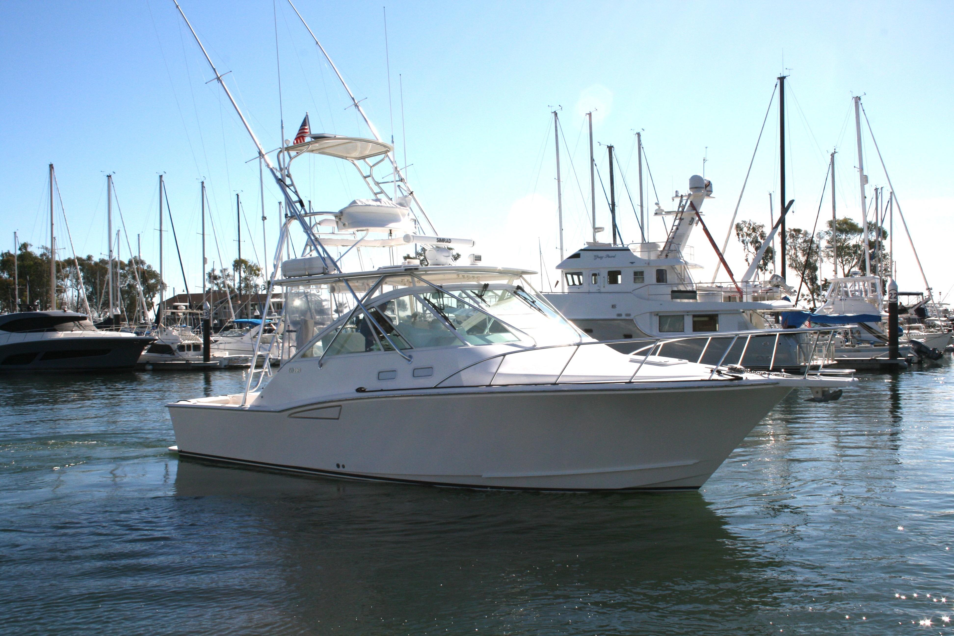 2005 Cabo 35 Express yacht docked in a marina with sailboats in the background.