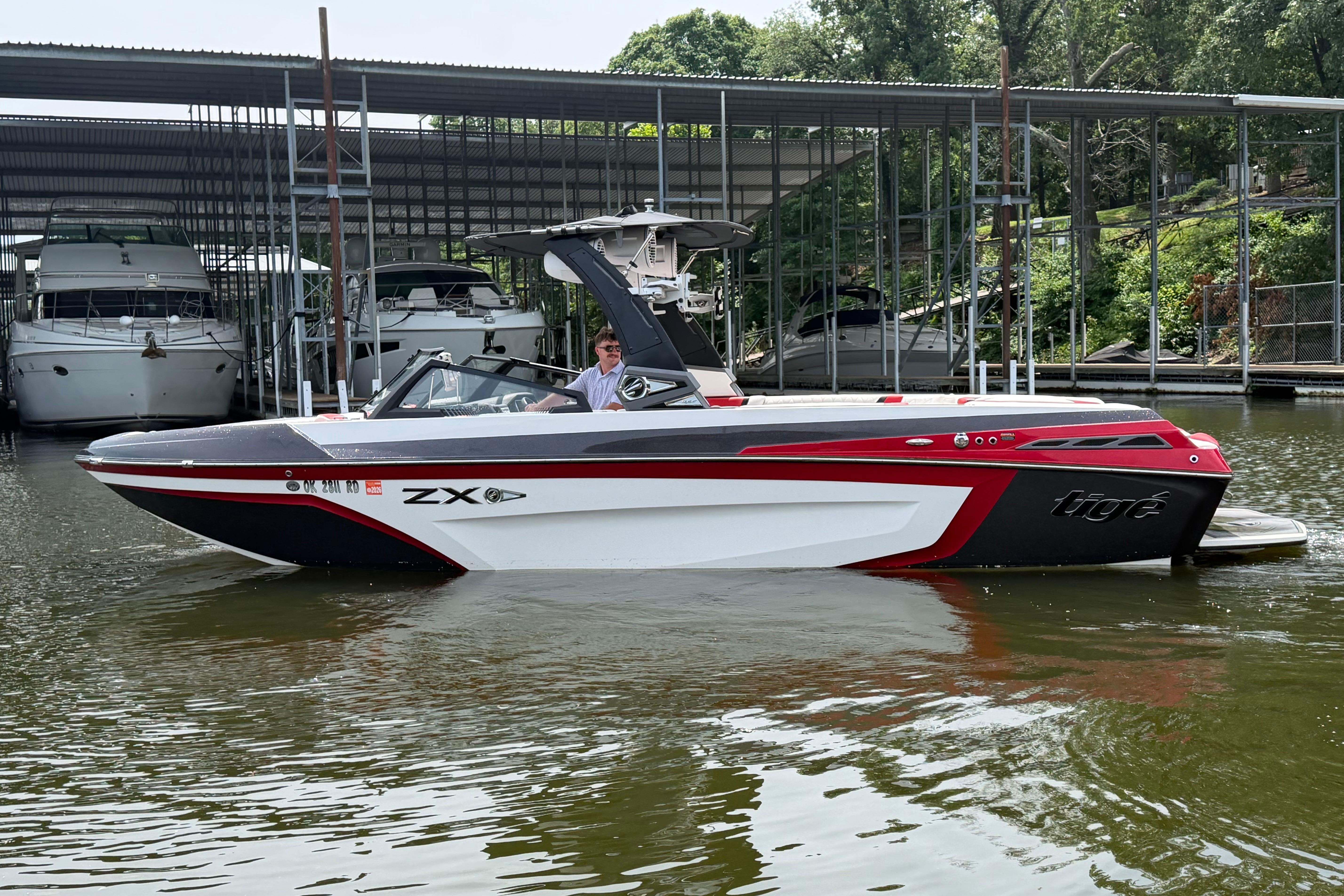 2020 Tige 25ZX boat docked in marina, featuring sleek red and white design.
