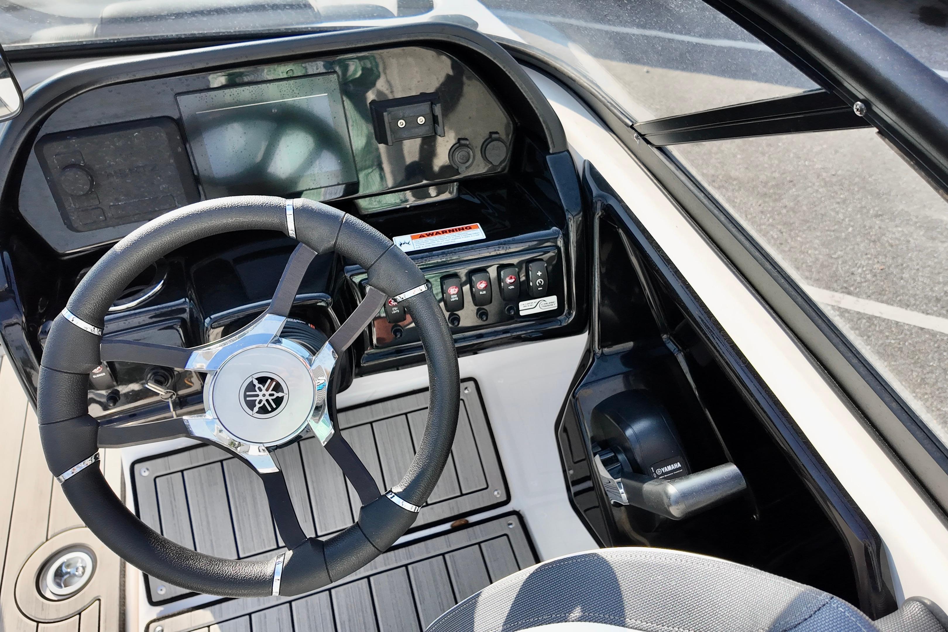 Steering console of 2023 Yamaha 195S boat with controls and display.