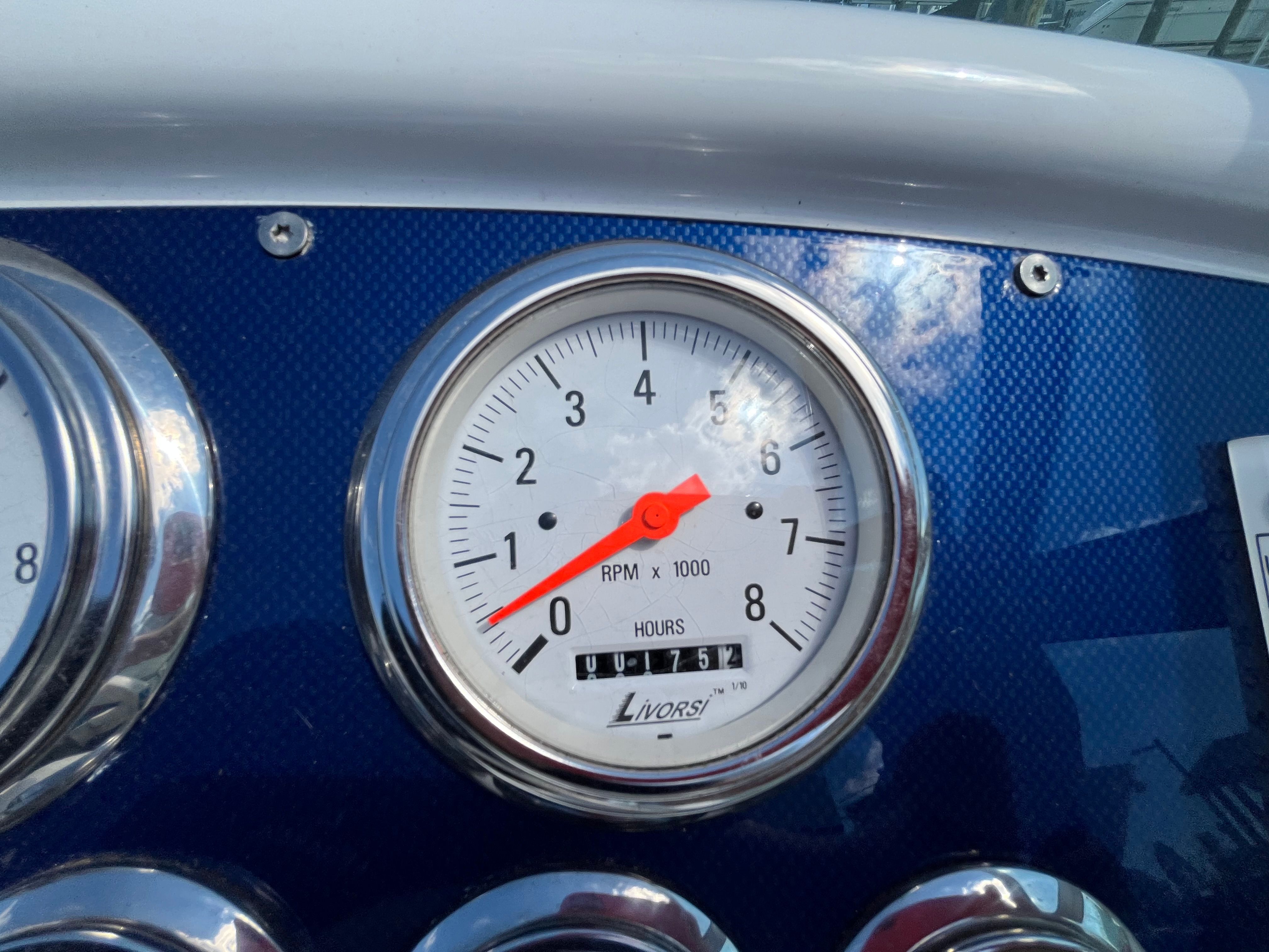 Close-up of a tachometer with a red needle on a blue background.