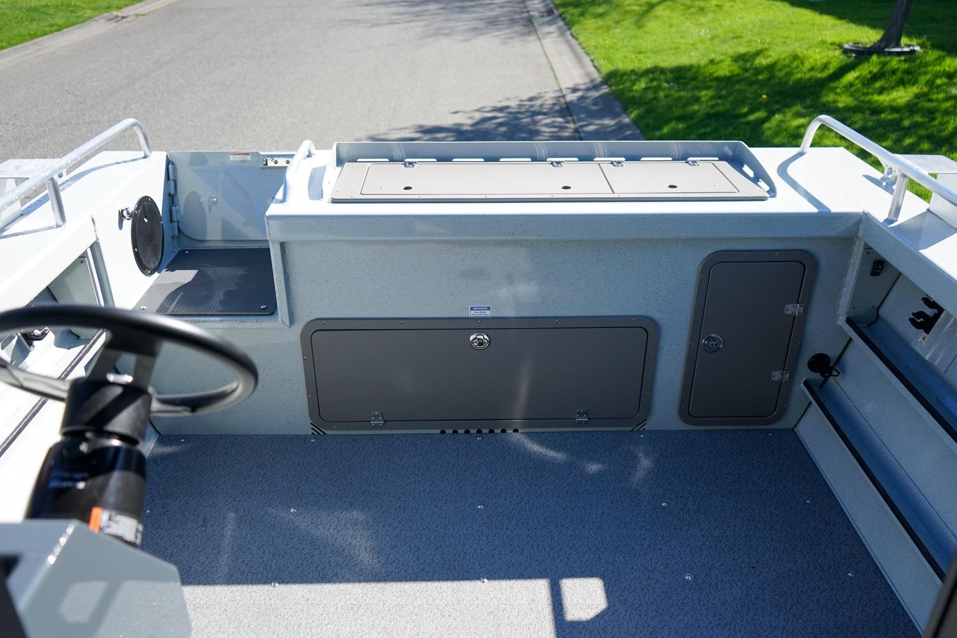 Interior view of 2026 Weldcraft 210 Revolution boat, showcasing storage compartments and steering wheel.