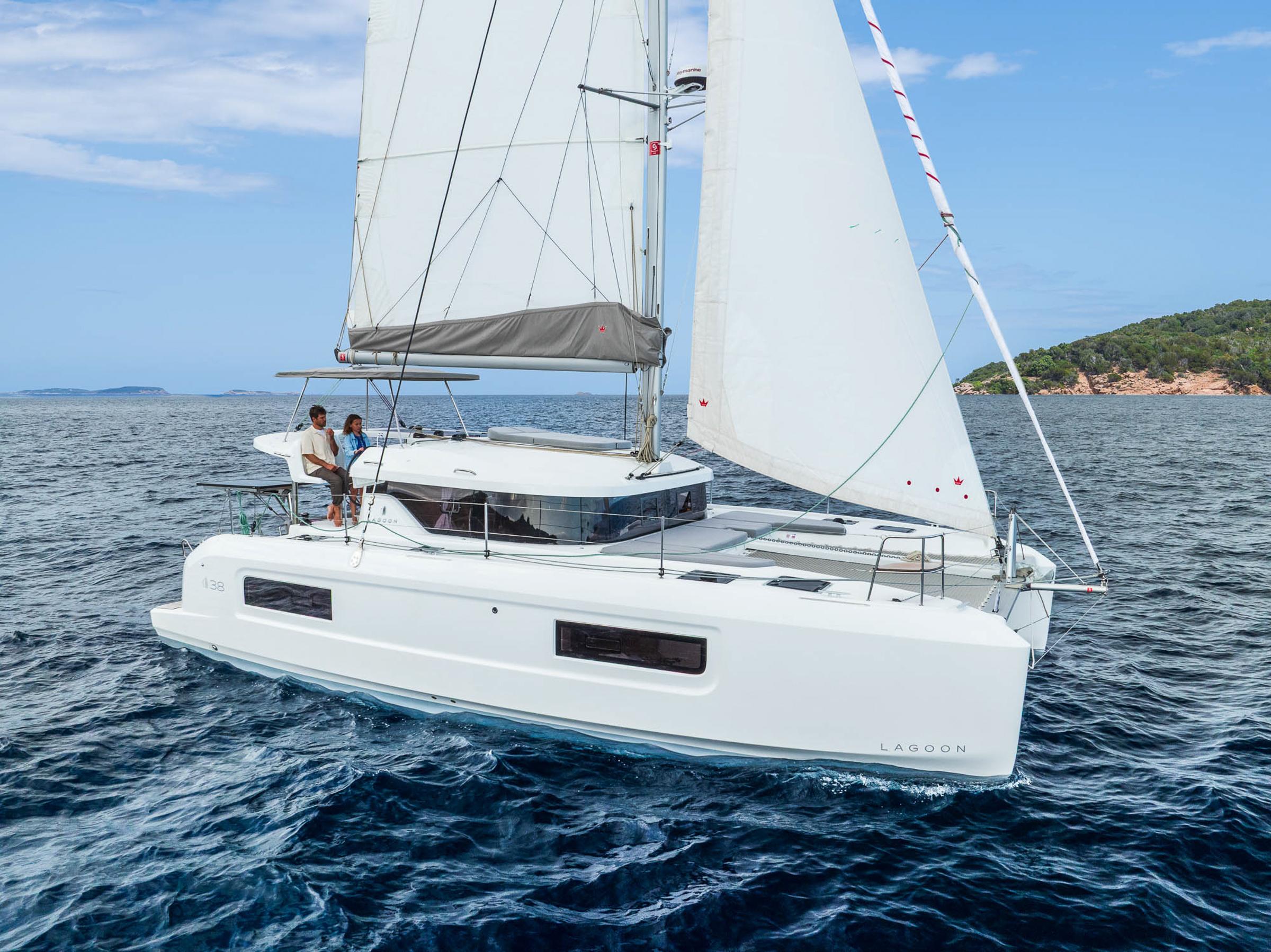 2025 Lagoon 38 catamaran sailing on open sea with two people onboard.
