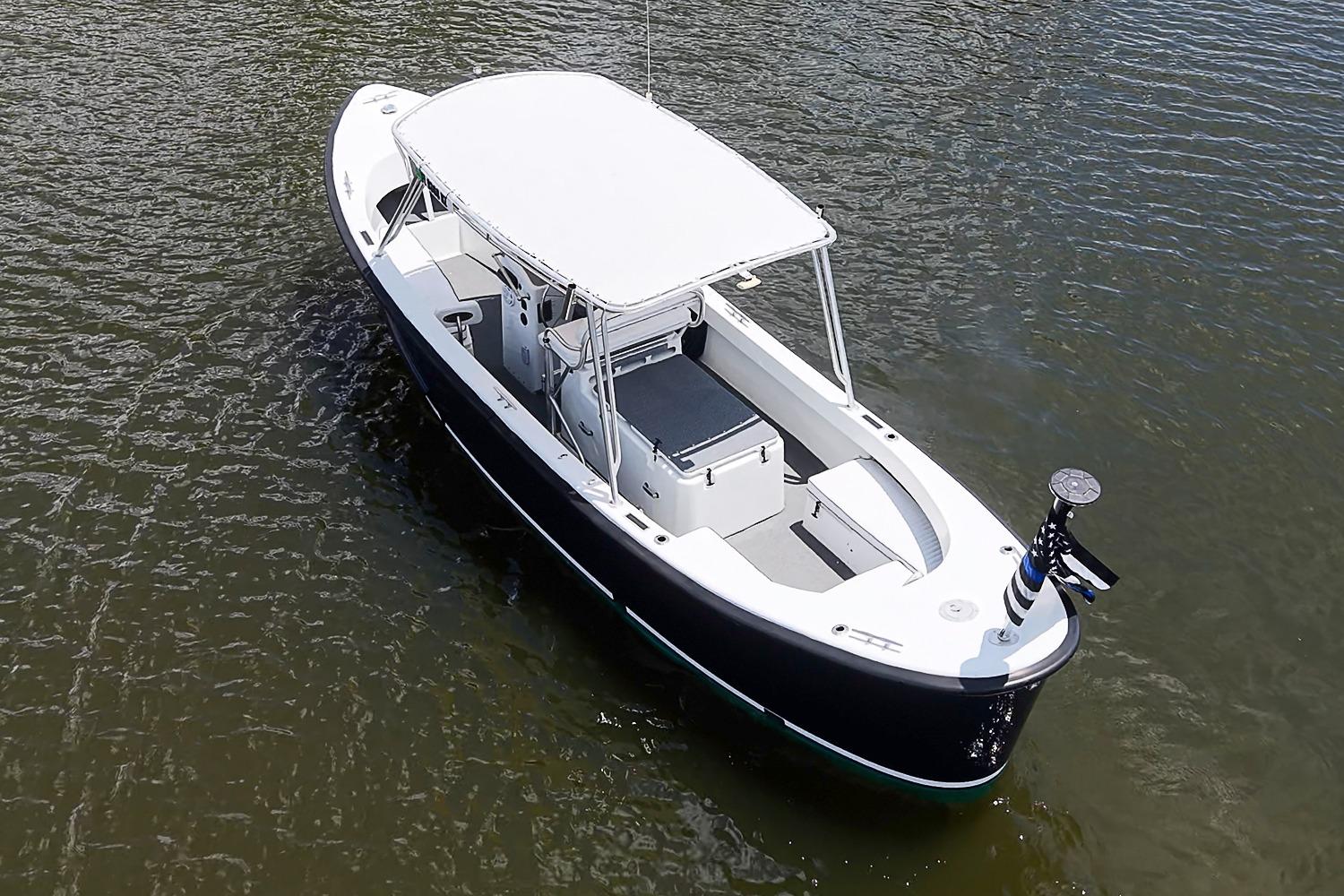 Custom 1969 boat with white canopy on calm water, aerial view.