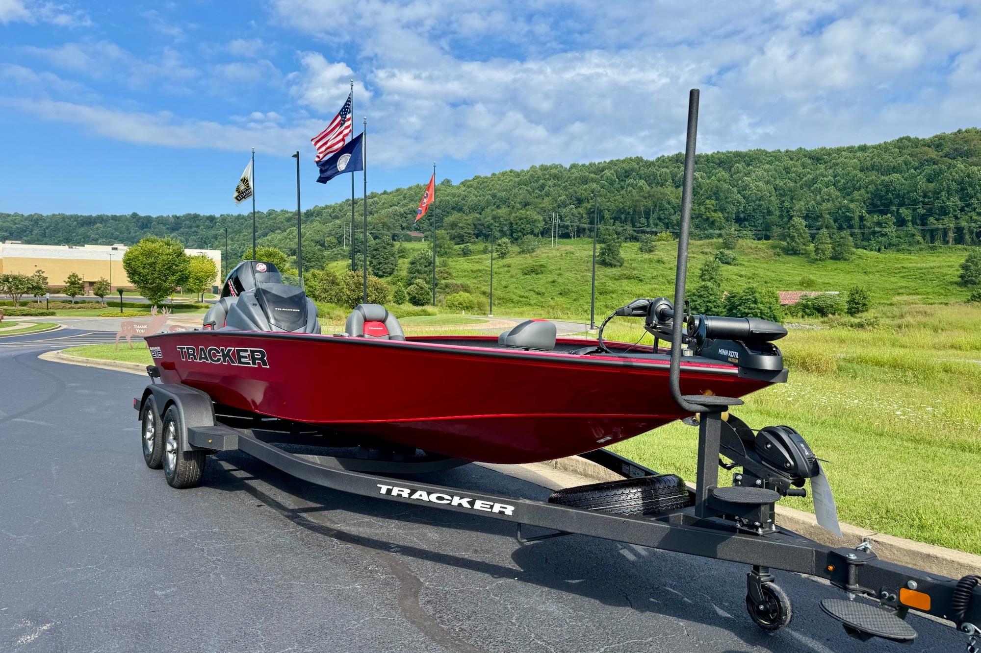 2026 Tracker Savage 215 boat on trailer, parked outdoors with flags and greenery.