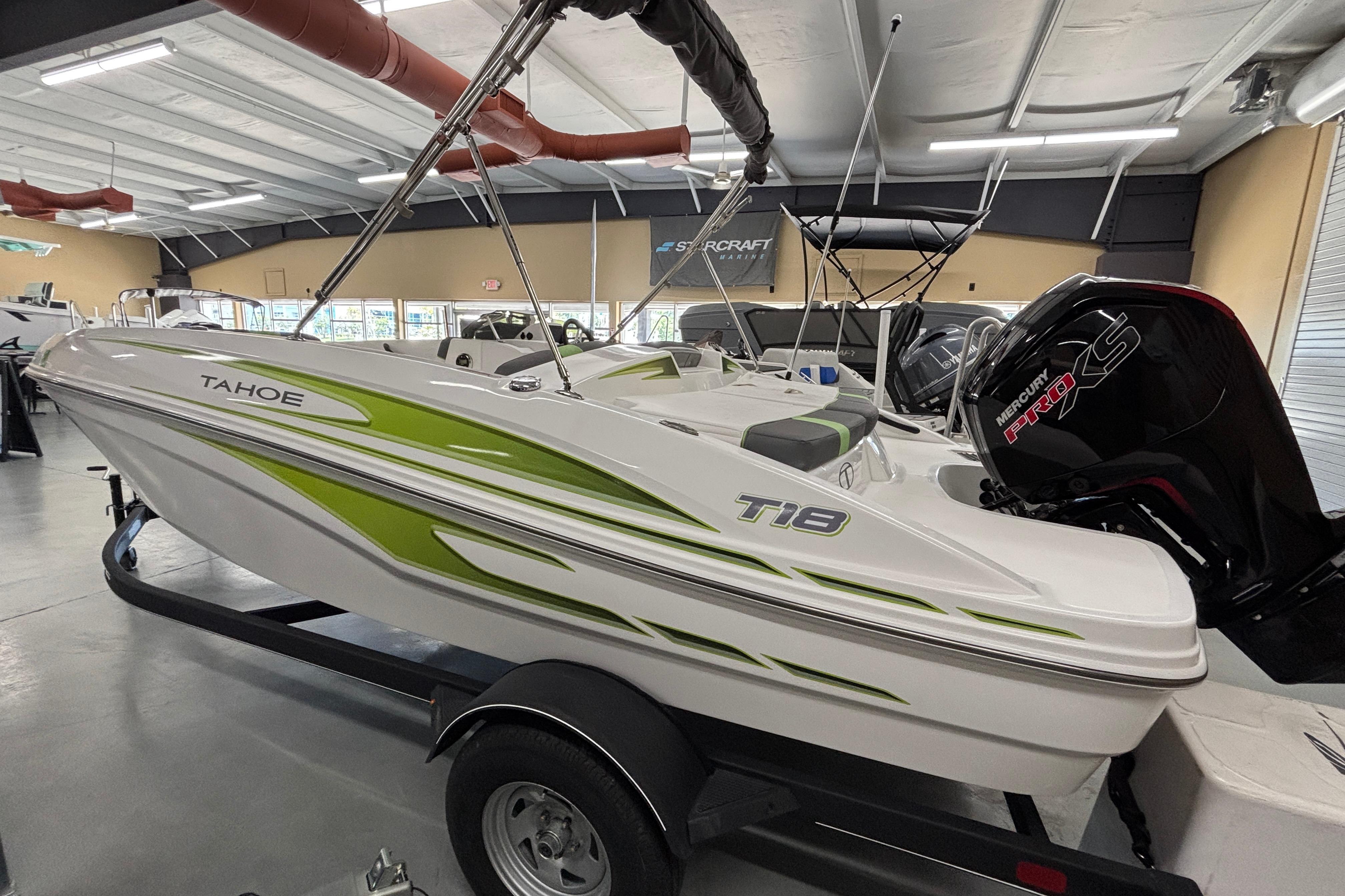 2024 Tahoe T18 boat with green accents on display in a showroom.