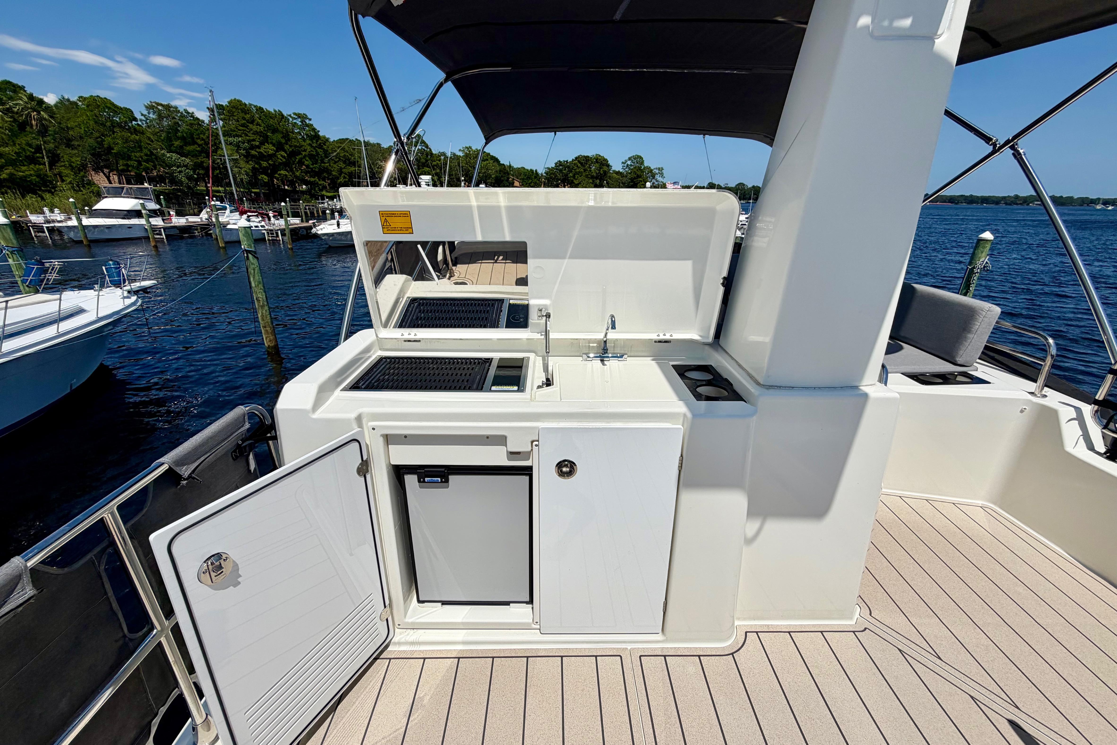 2025 Beneteau Swift Trawler 41 Fly deck with outdoor kitchenette and scenic marina view.