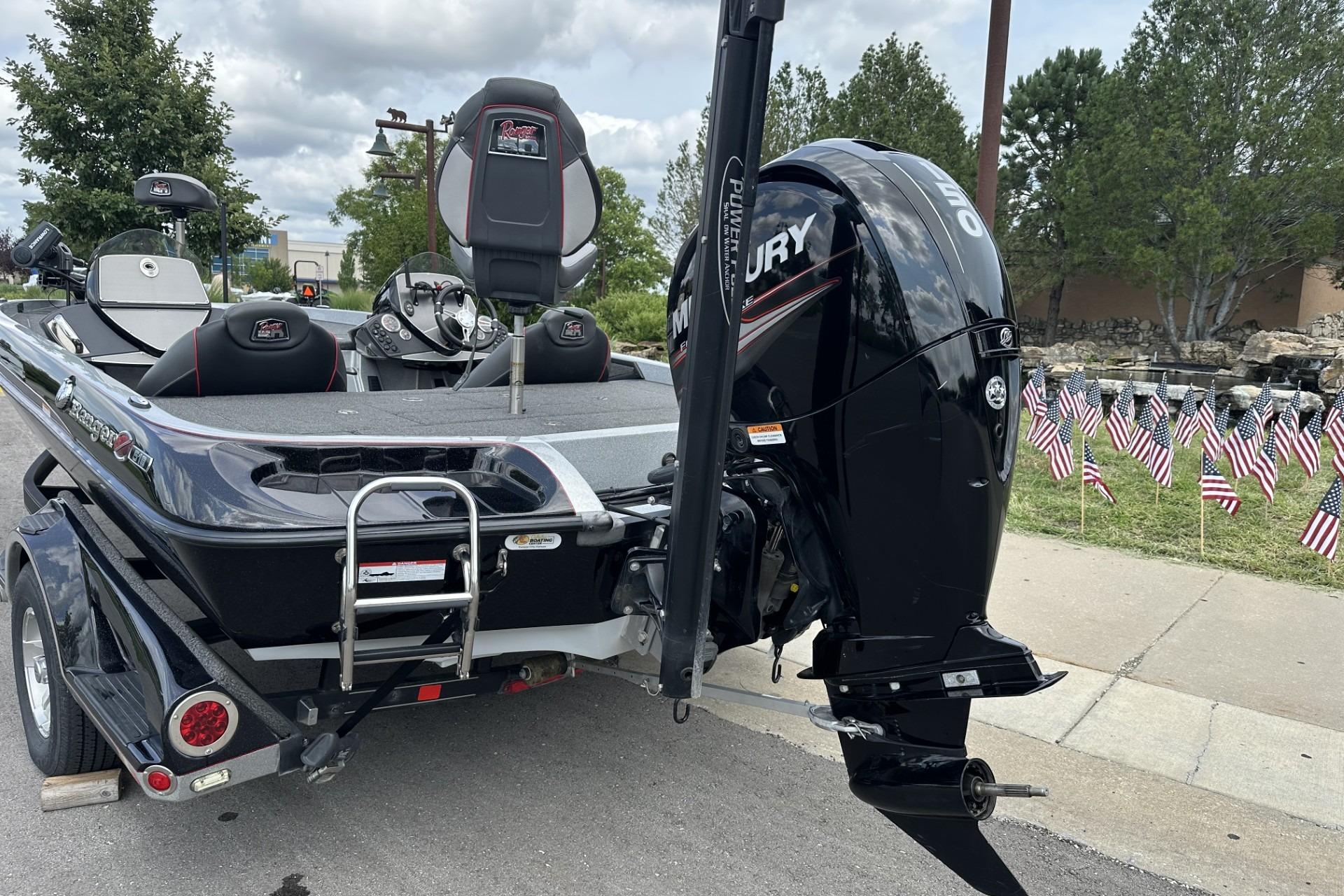 2018 Ranger Z518 boat with Mercury engine, parked near American flags on a trailer.