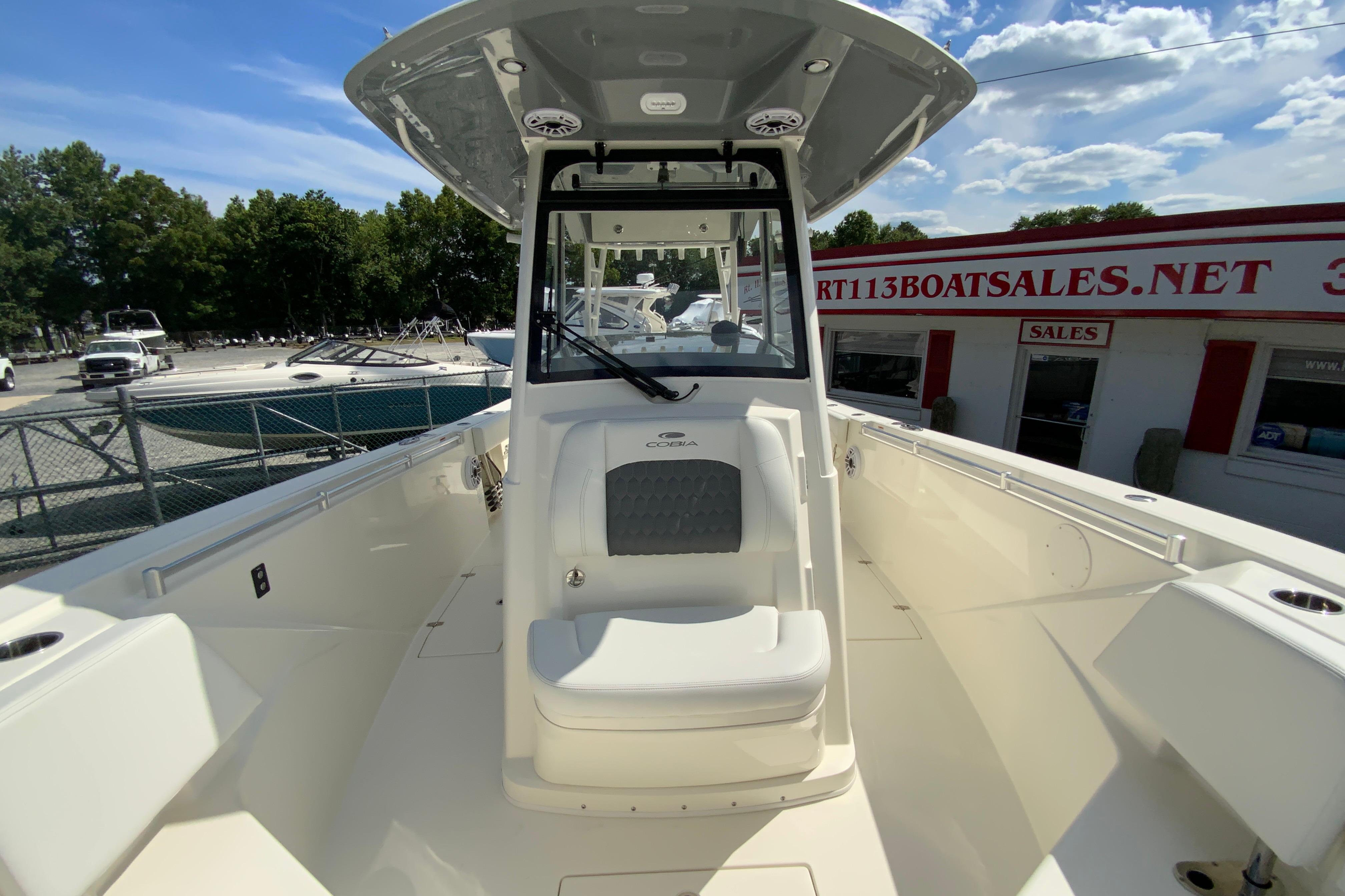 2027 Cobia 320 Center Console boat at dealership, sunny day, clear sky.