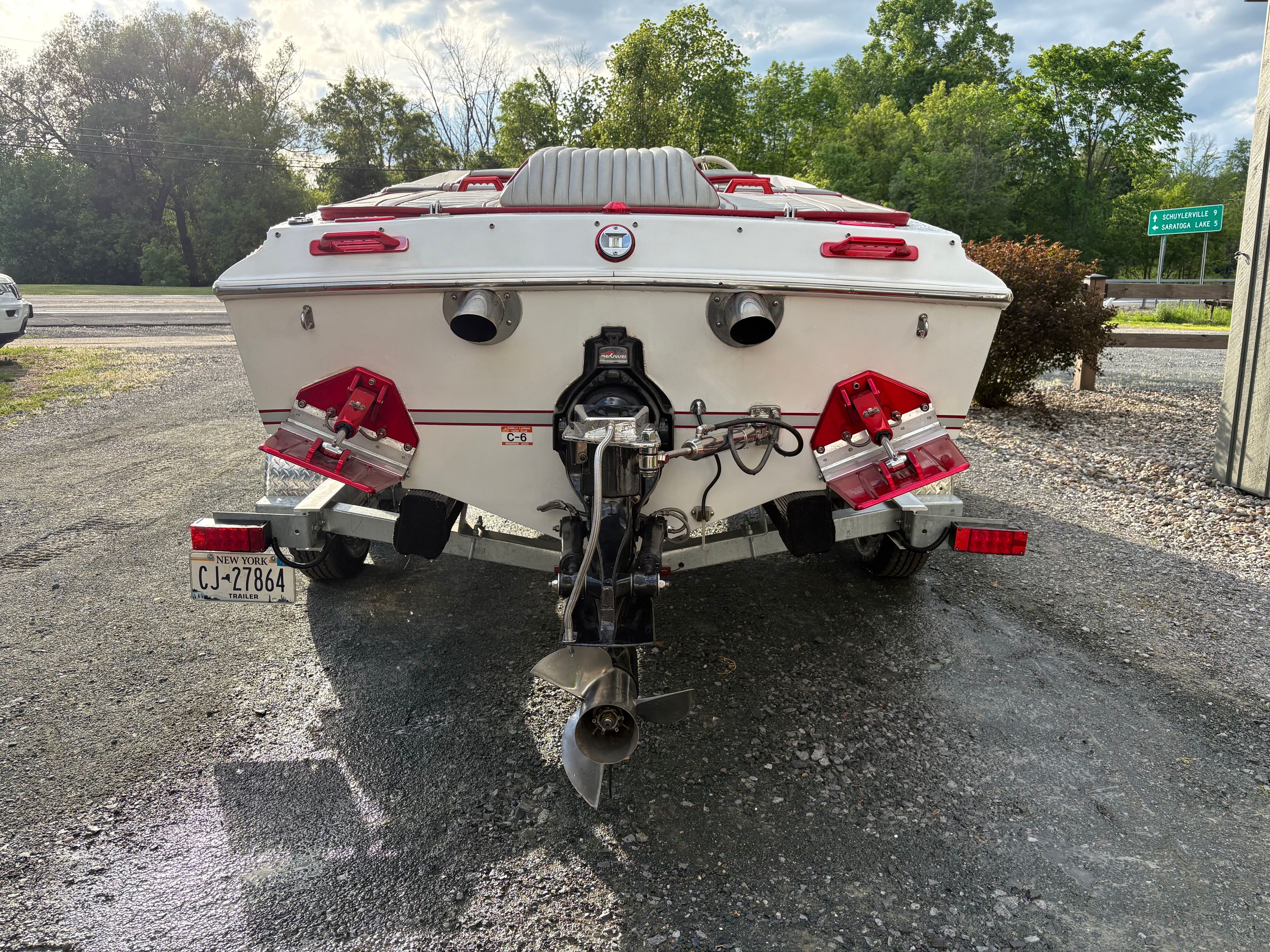 The image shows the rear of a white 1986 Warlock 23 boat with dual exhaust pipes.