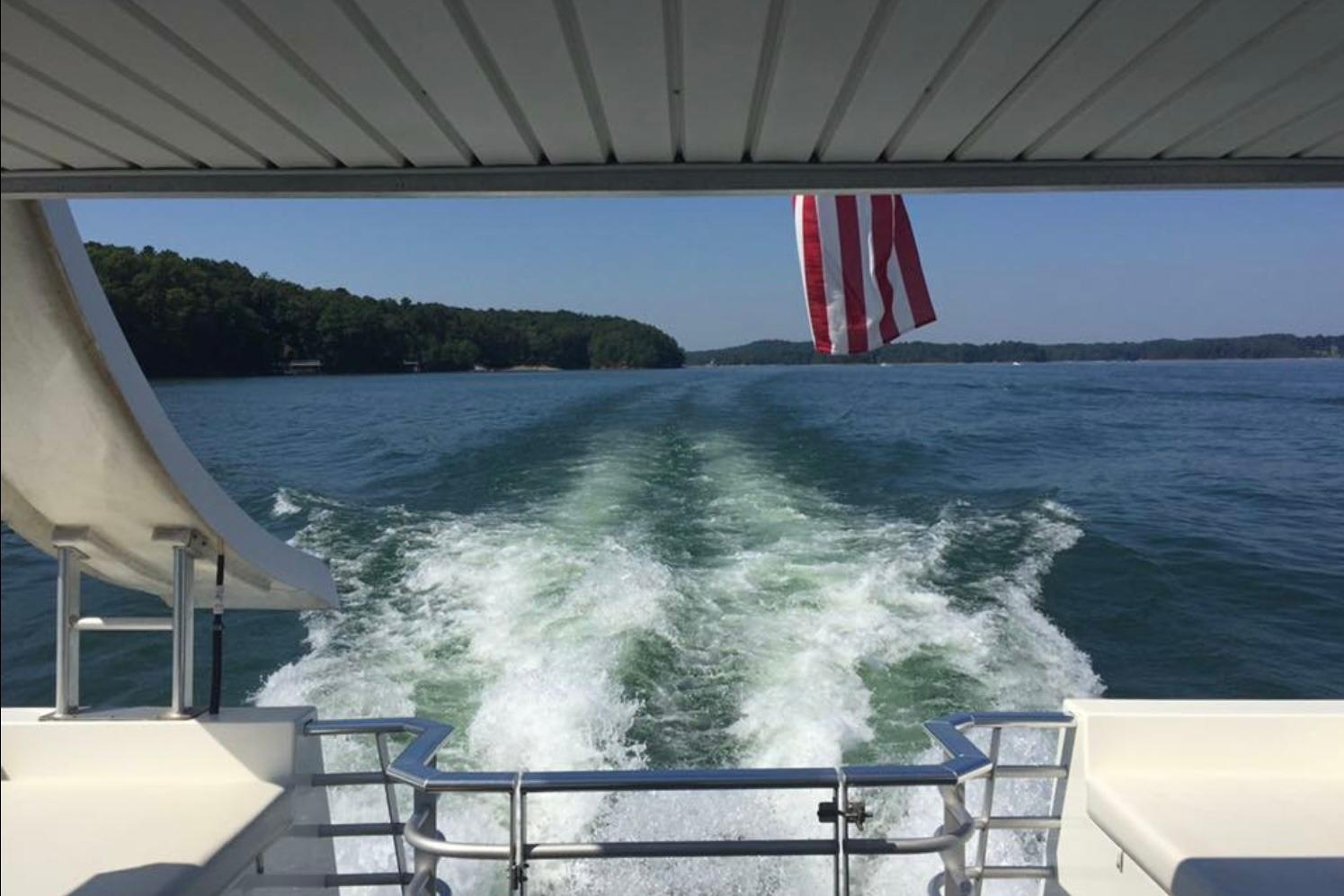 2008 Destination Yachts 45X14 cruising on a lake with American flag and wake view.