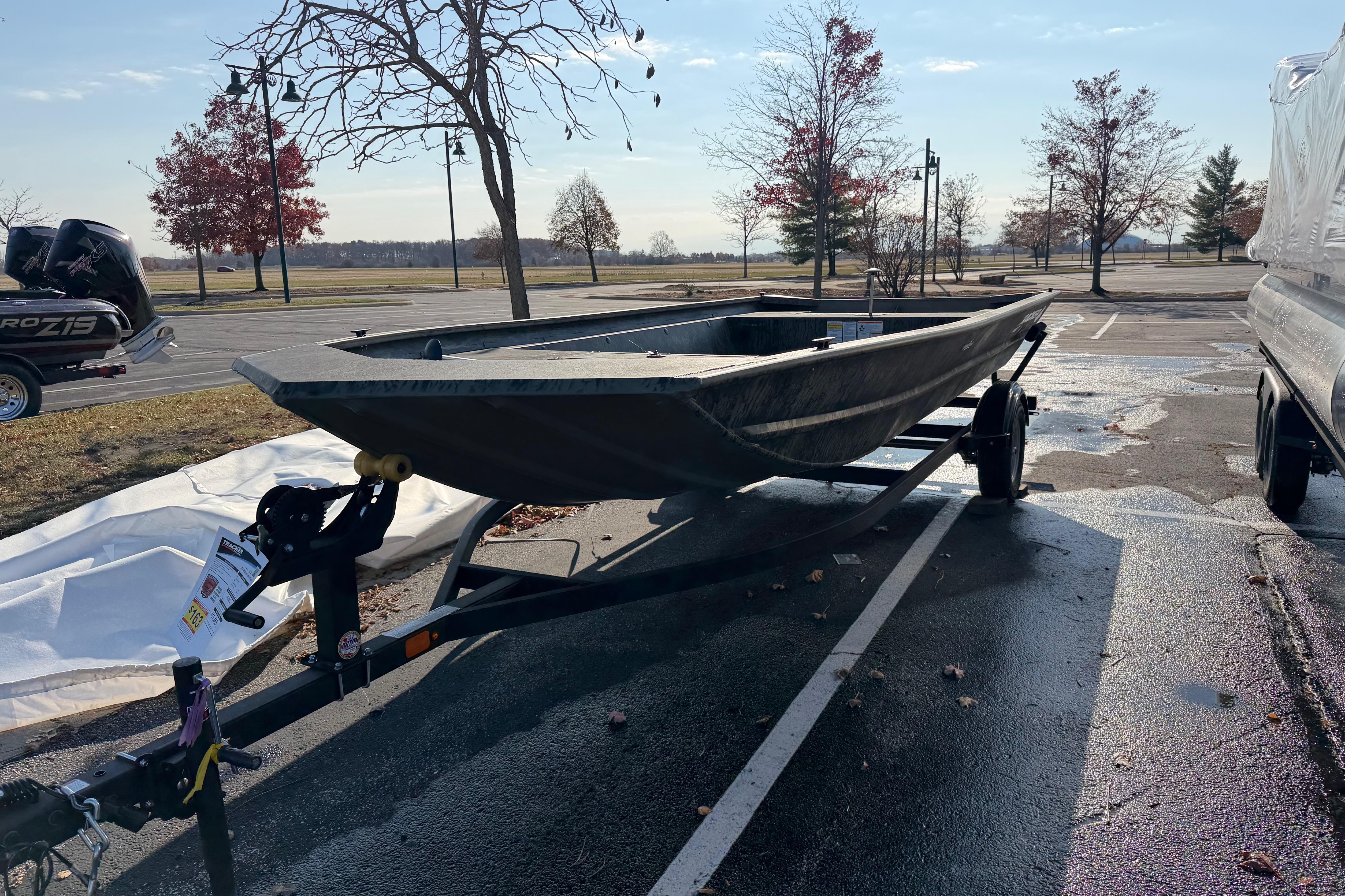 2026 Tracker Grizzly 1860 Utility boat on trailer in parking lot.