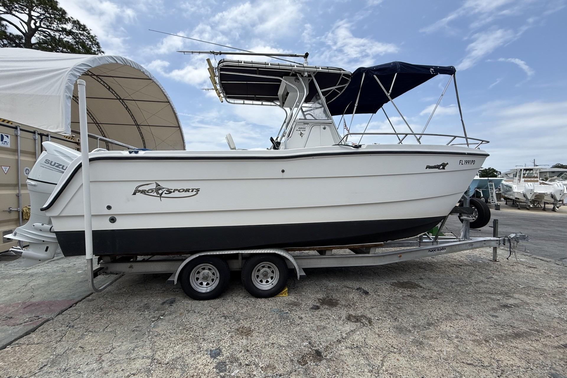 2002 Pro Sports 2200 CC ProKat boat on trailer, parked outdoors under a cloudy sky.