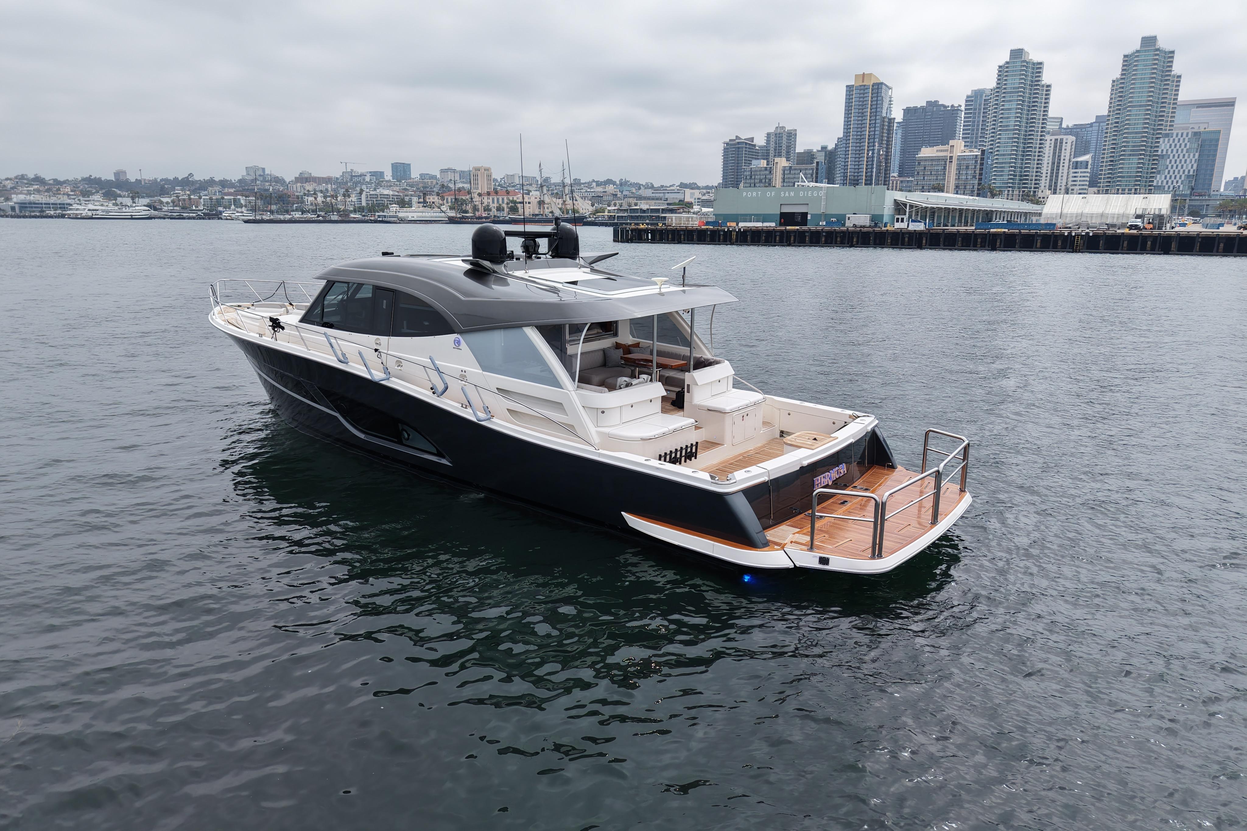 Luxury 2023 Riviera 645 SUV yacht cruising near city skyline.
