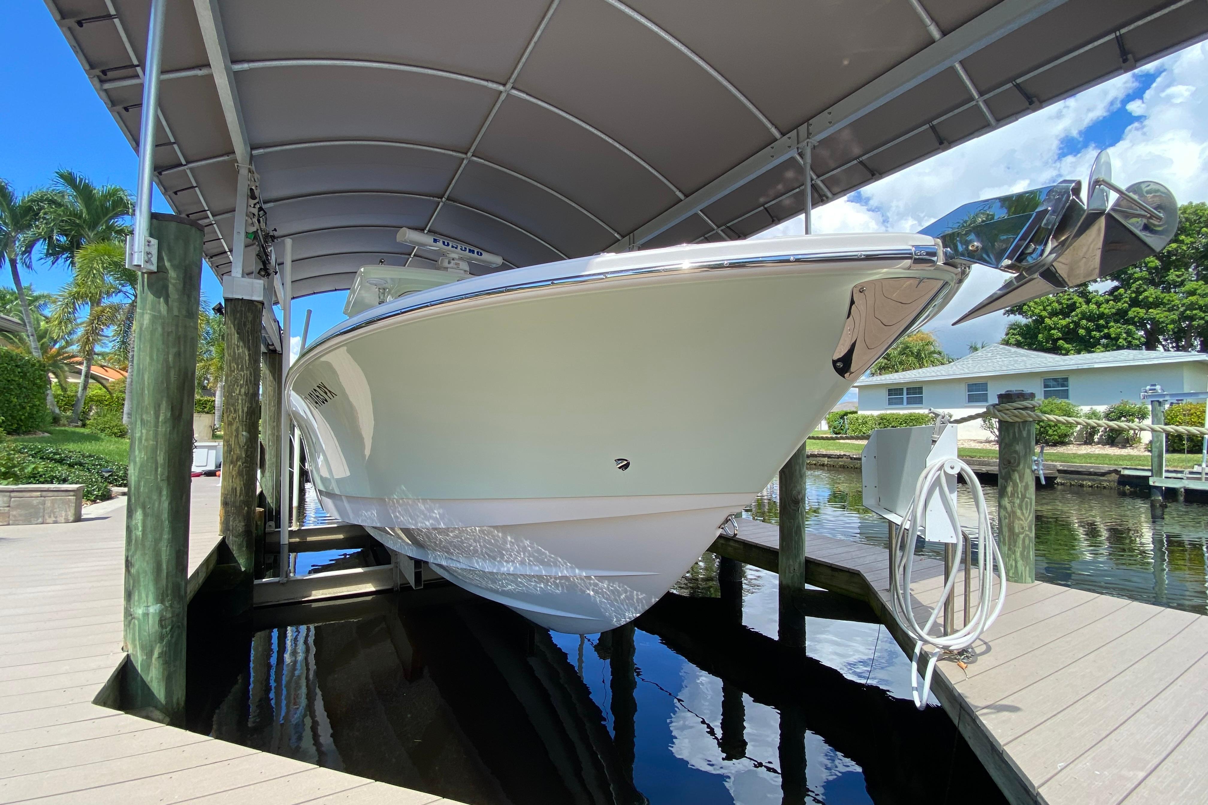 2015 Edgewater 320CC boat docked under canopy, surrounded by tropical scenery.