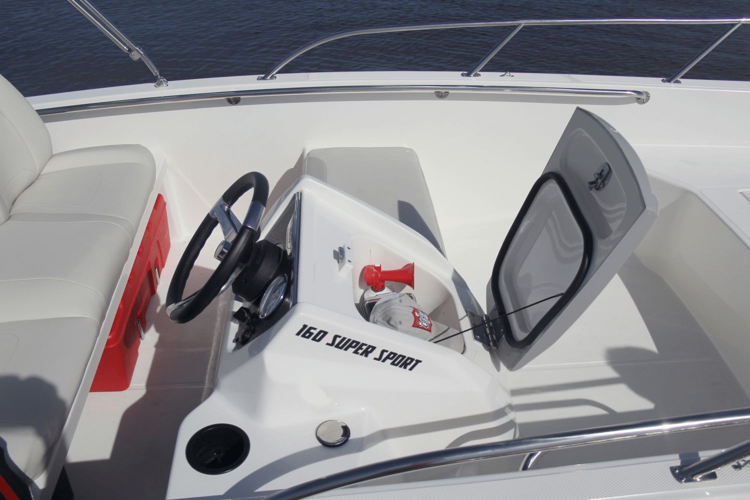 The image shows the cockpit of a Boston Whaler 160 Super Sport with an open storage compartment.