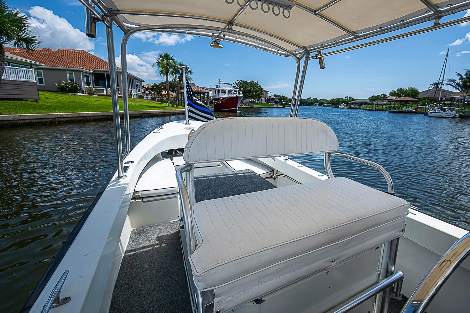 Custom 1969 boat with white seating, cruising on a scenic canal under a clear blue sky.