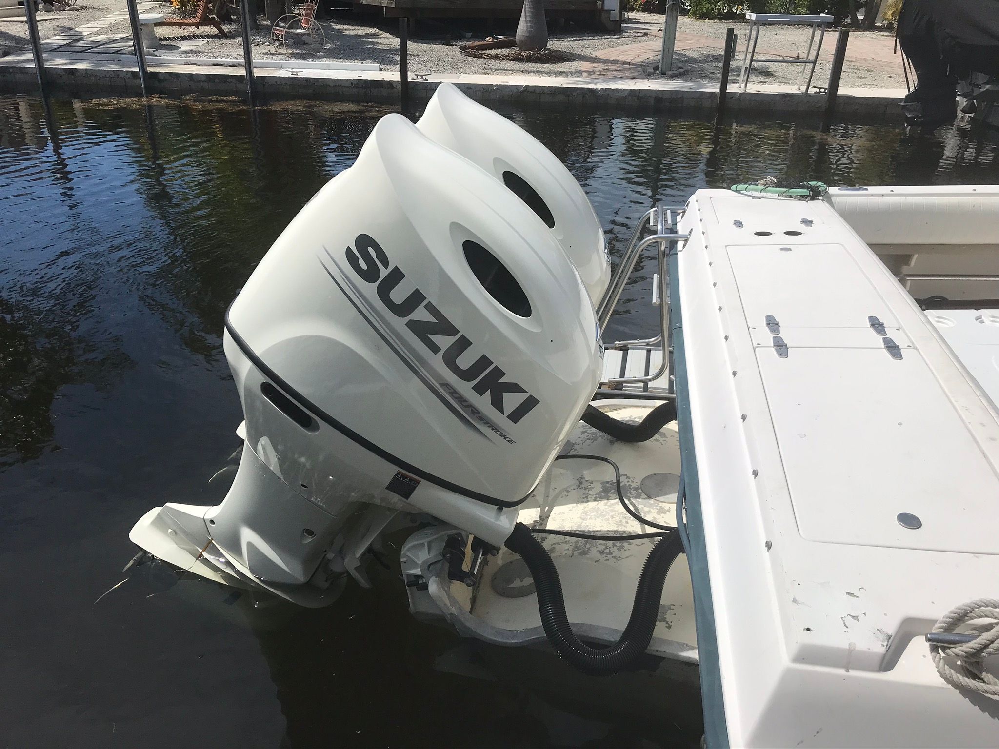 Two Suzuki outboard engines on a Grady-White boat docked by the water.