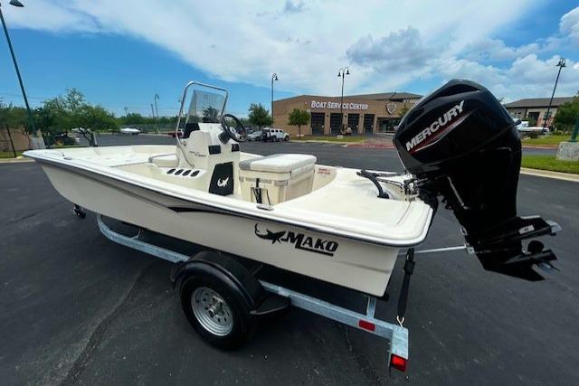 2026 Mako Pro Skiff 15 CC boat with Mercury engine on trailer, parked outdoors.