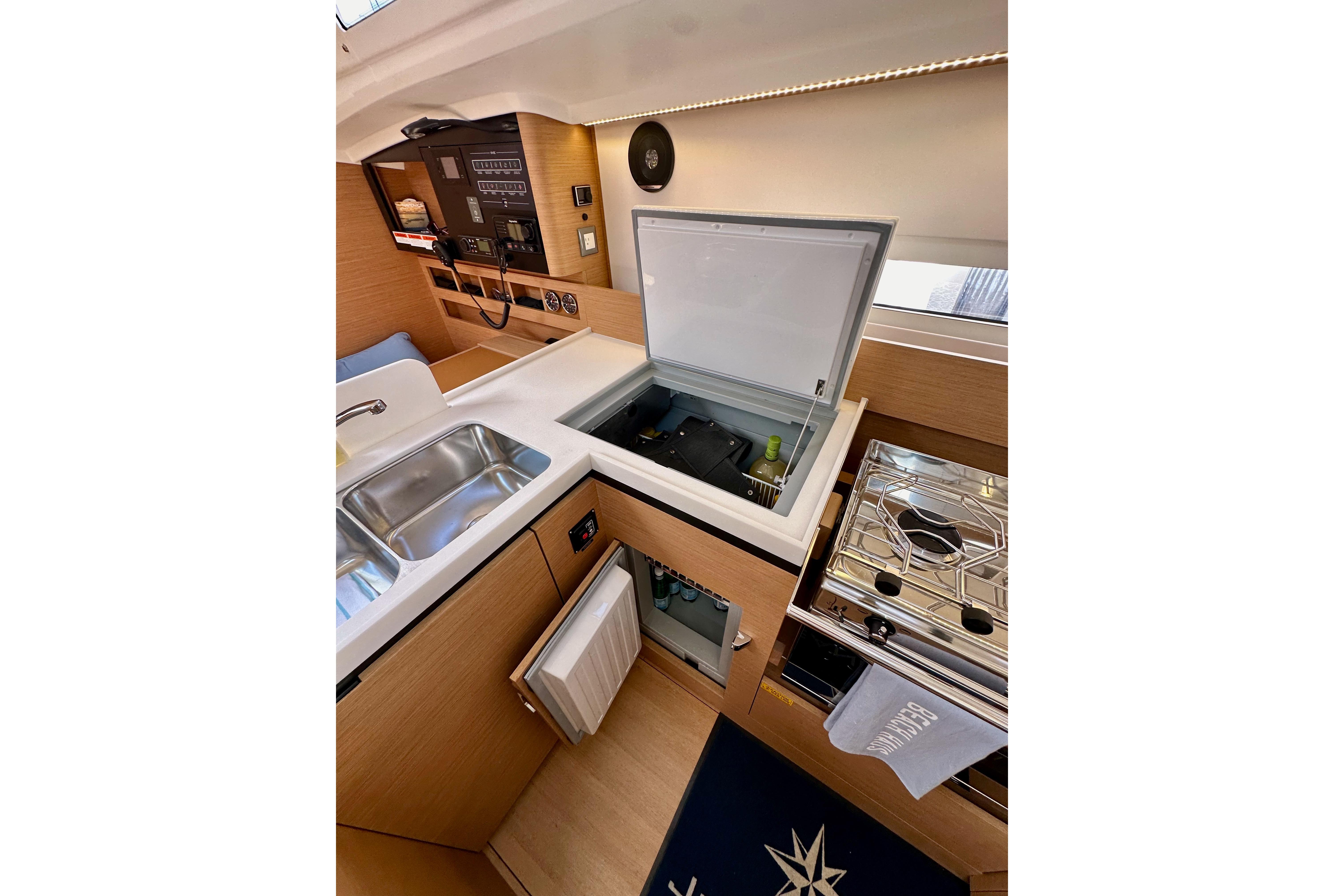 Modern kitchen interior of 2024 Jeanneau Sun Odyssey 410 yacht, featuring sink, stove, and storage.