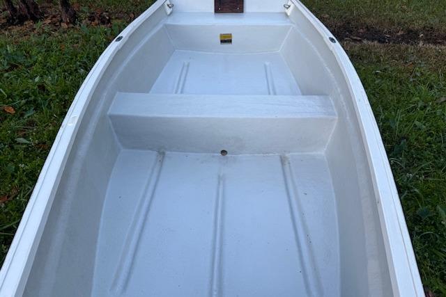 White 1999 Beacon Boats Pram on grass, showcasing interior seating and structure.