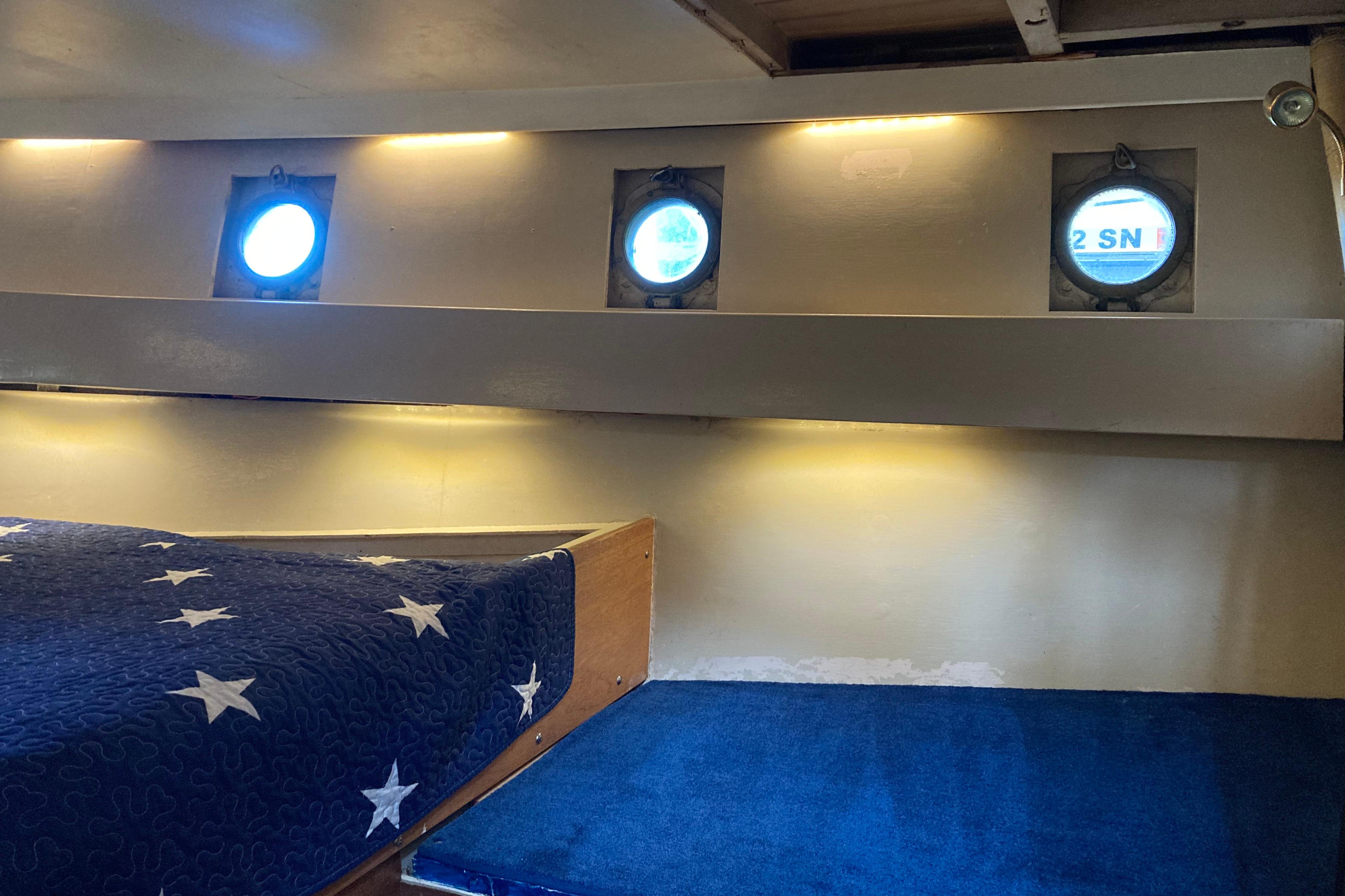 Interior of 1942 Grenfell 42 Custom boat with portholes and star-patterned bedding.