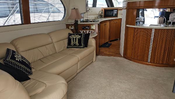 Interior of 2000 Carver 450 Voyager Pilothouse with beige leather sofa and wooden cabinetry.