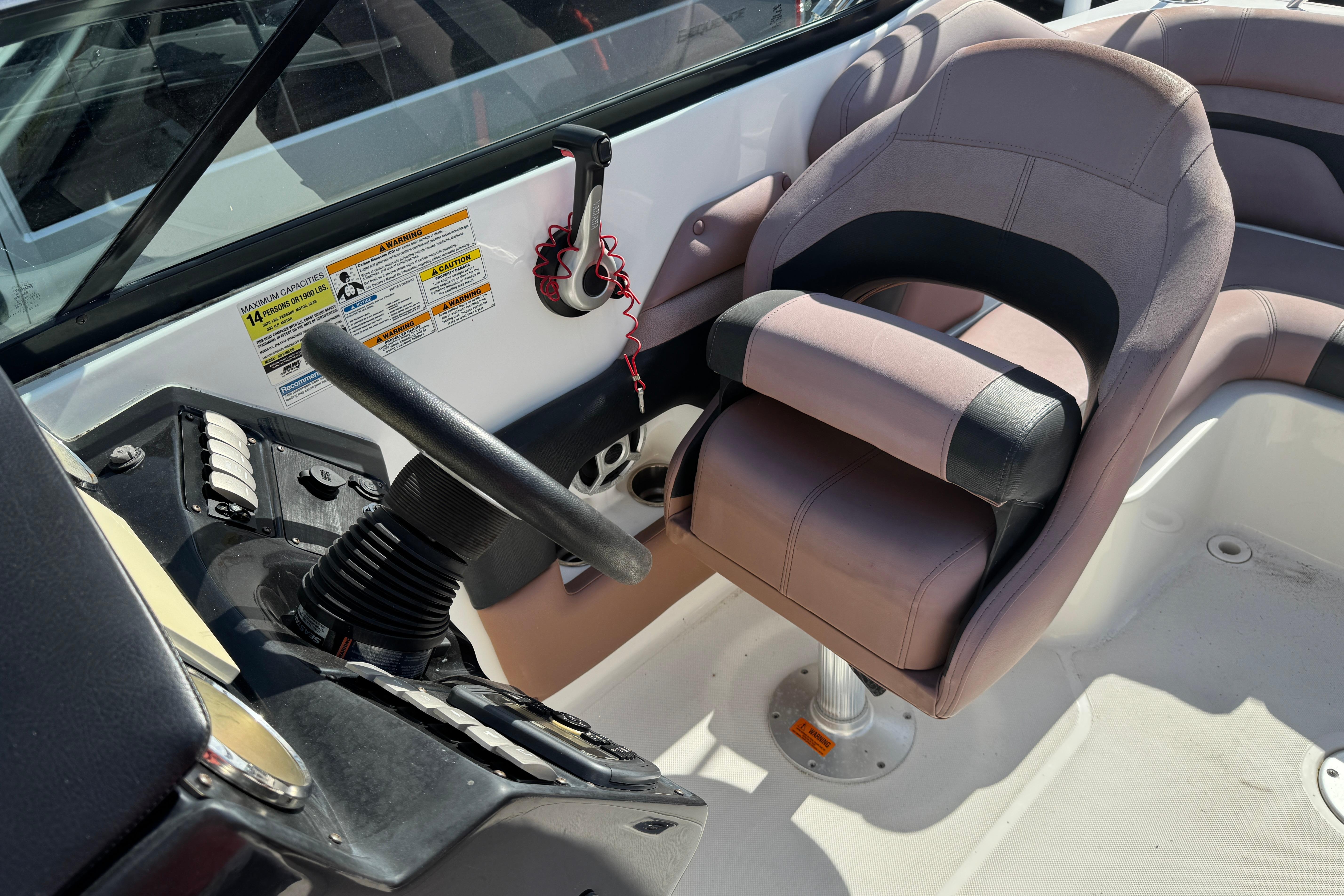 2018 Hurricane SunDeck 2400 OB boat cockpit with steering wheel and comfortable seating.