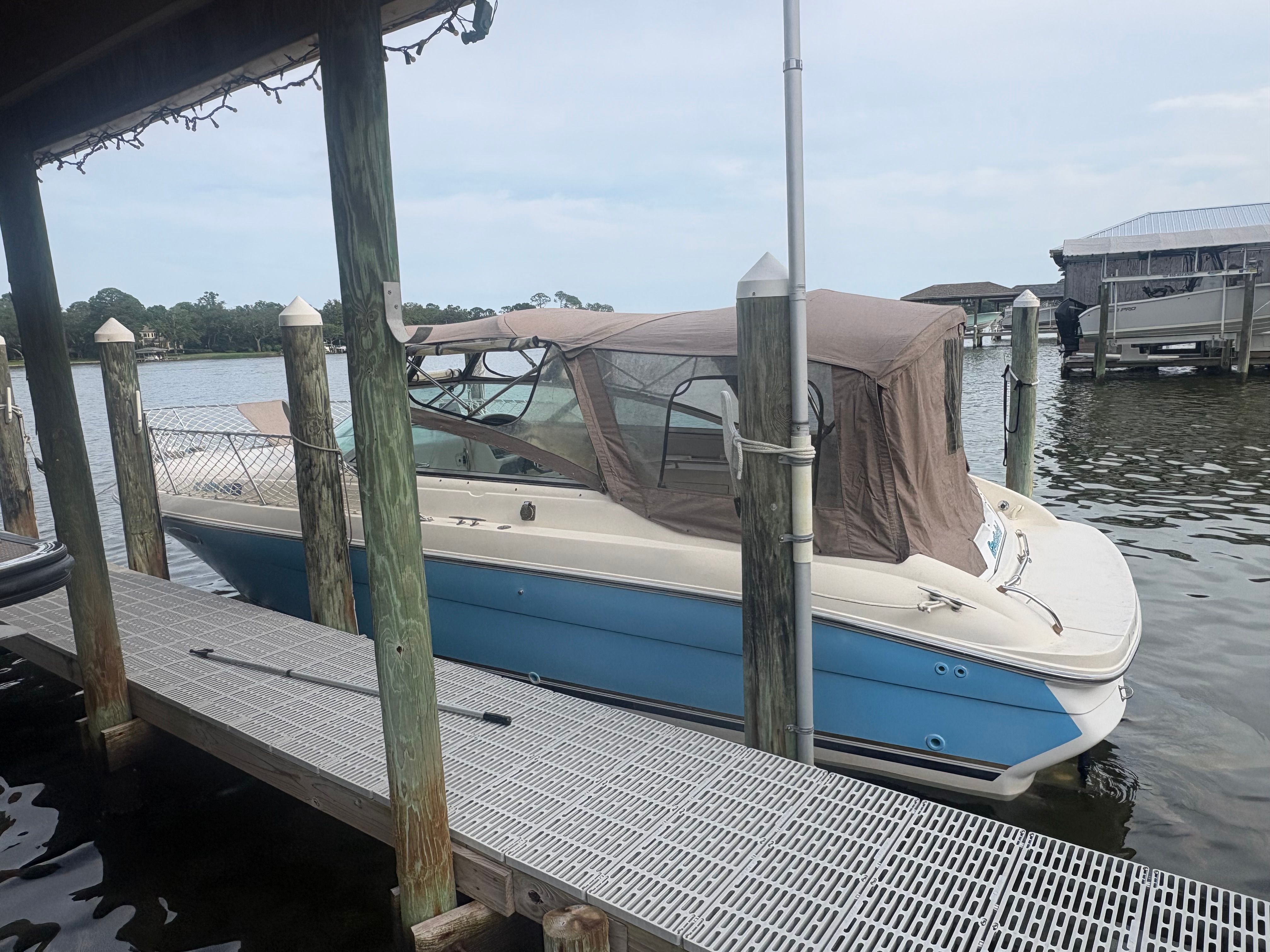 A blue and white 1996 Sea Ray 280 Cuddy Cabin is docked on the water.