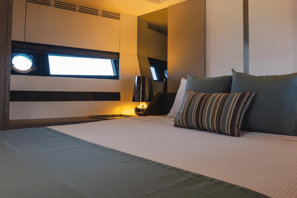 Luxurious bedroom interior of 2020 Azimut 60 yacht with elegant bedding and ambient lighting.