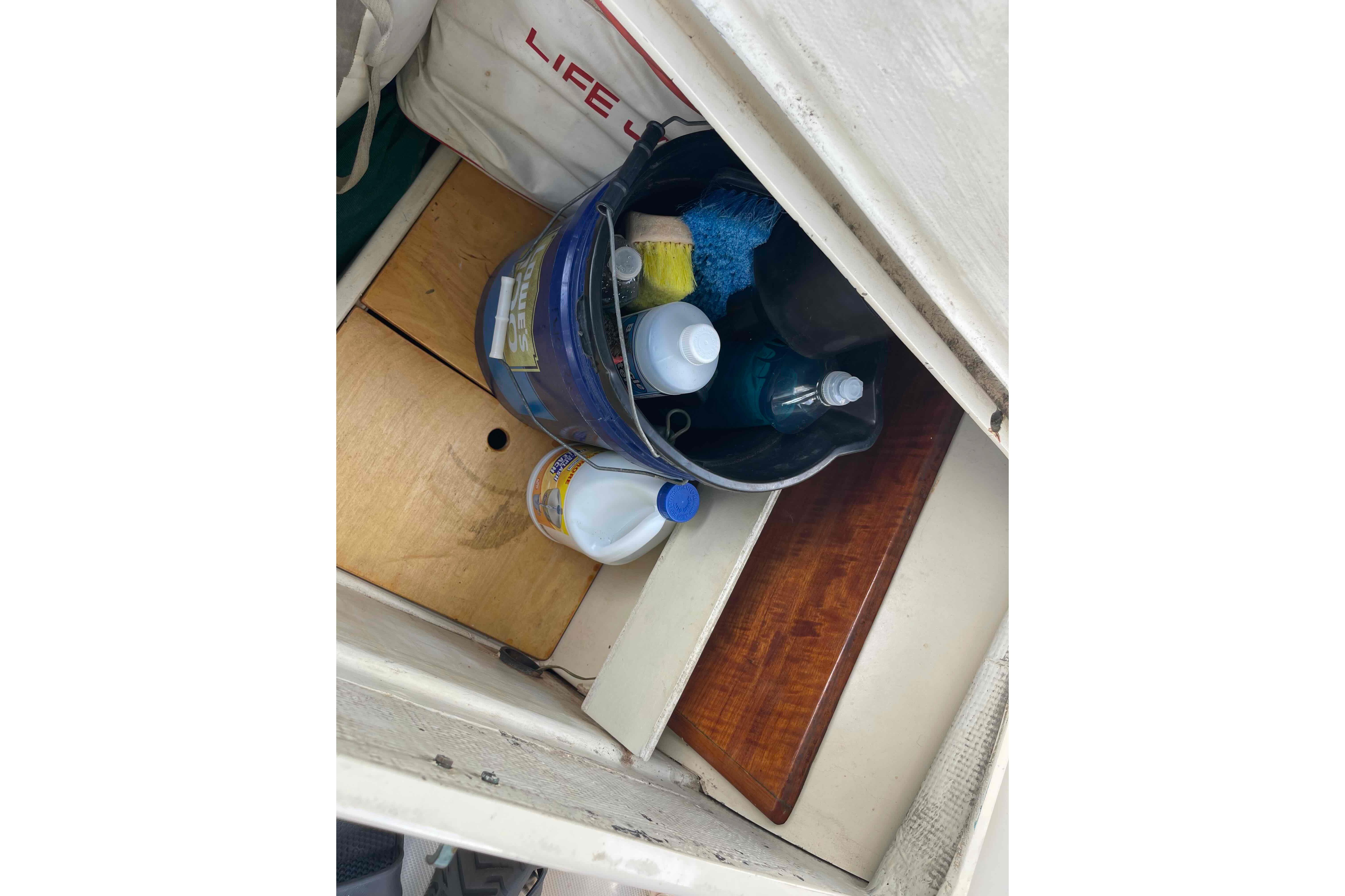 Storage compartment on a 1987 Pacific Seacraft 34 sailboat with cleaning supplies and life jacket.