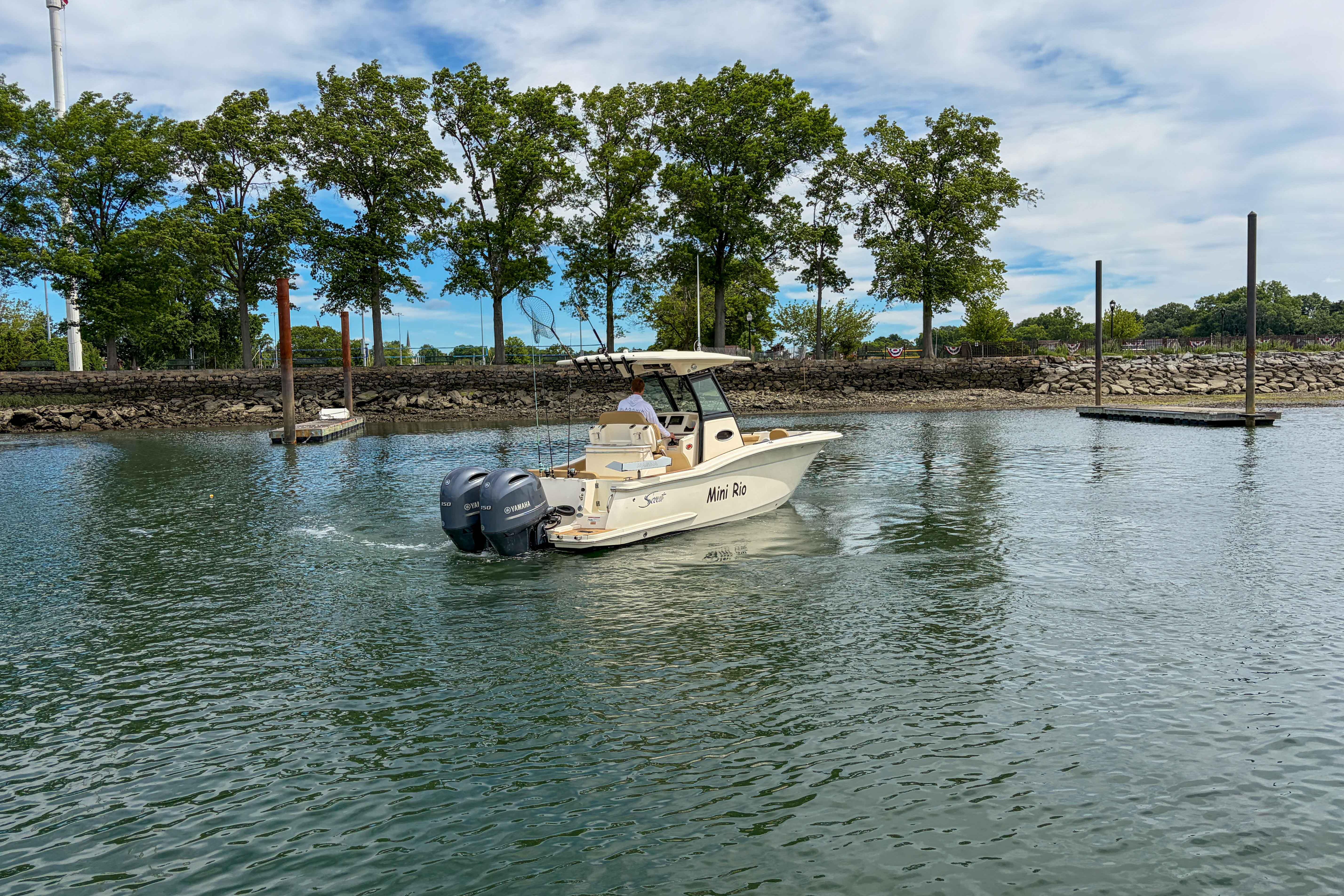 2020 Scout 255 LXF boat cruising on a calm lake with trees in the background.