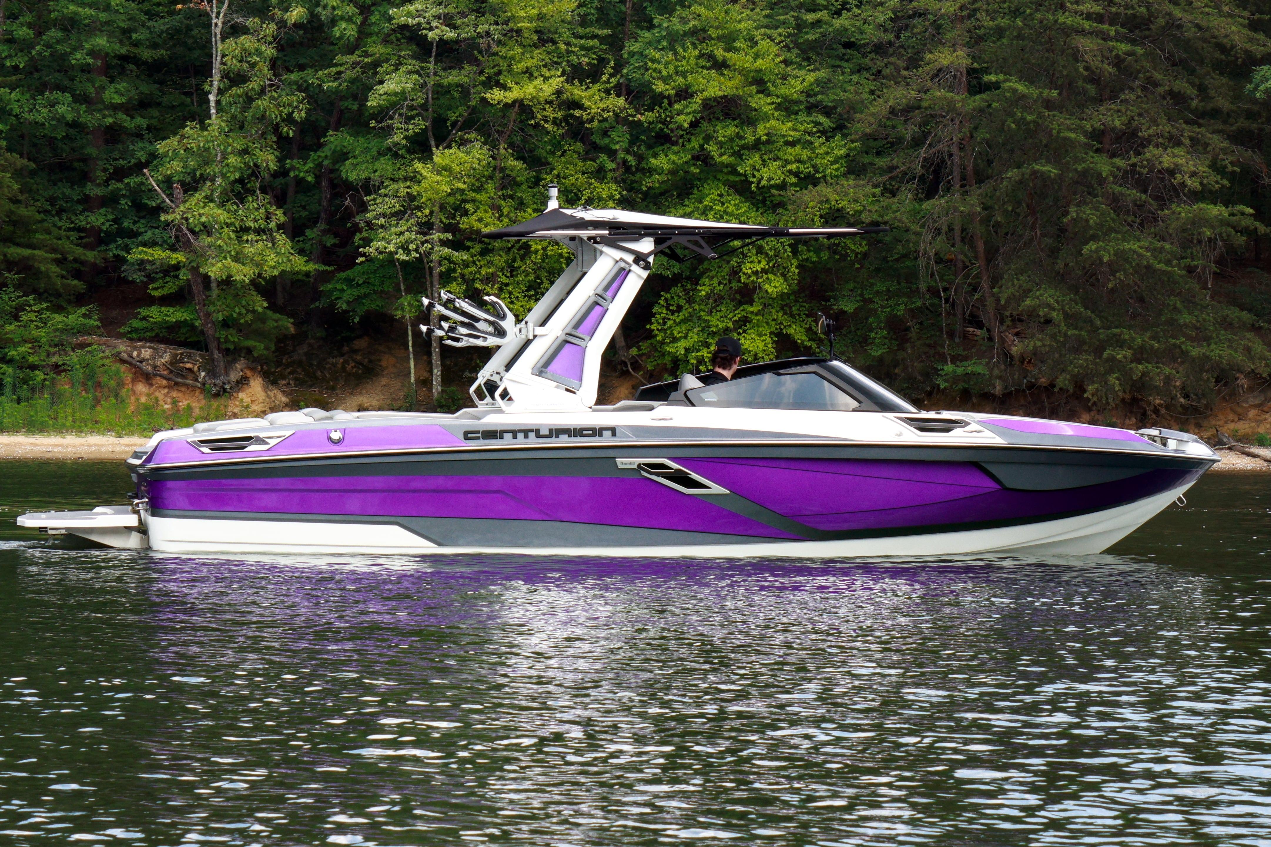 2022 Centurion Ri245 boat in vibrant purple on a serene lake, surrounded by lush trees.