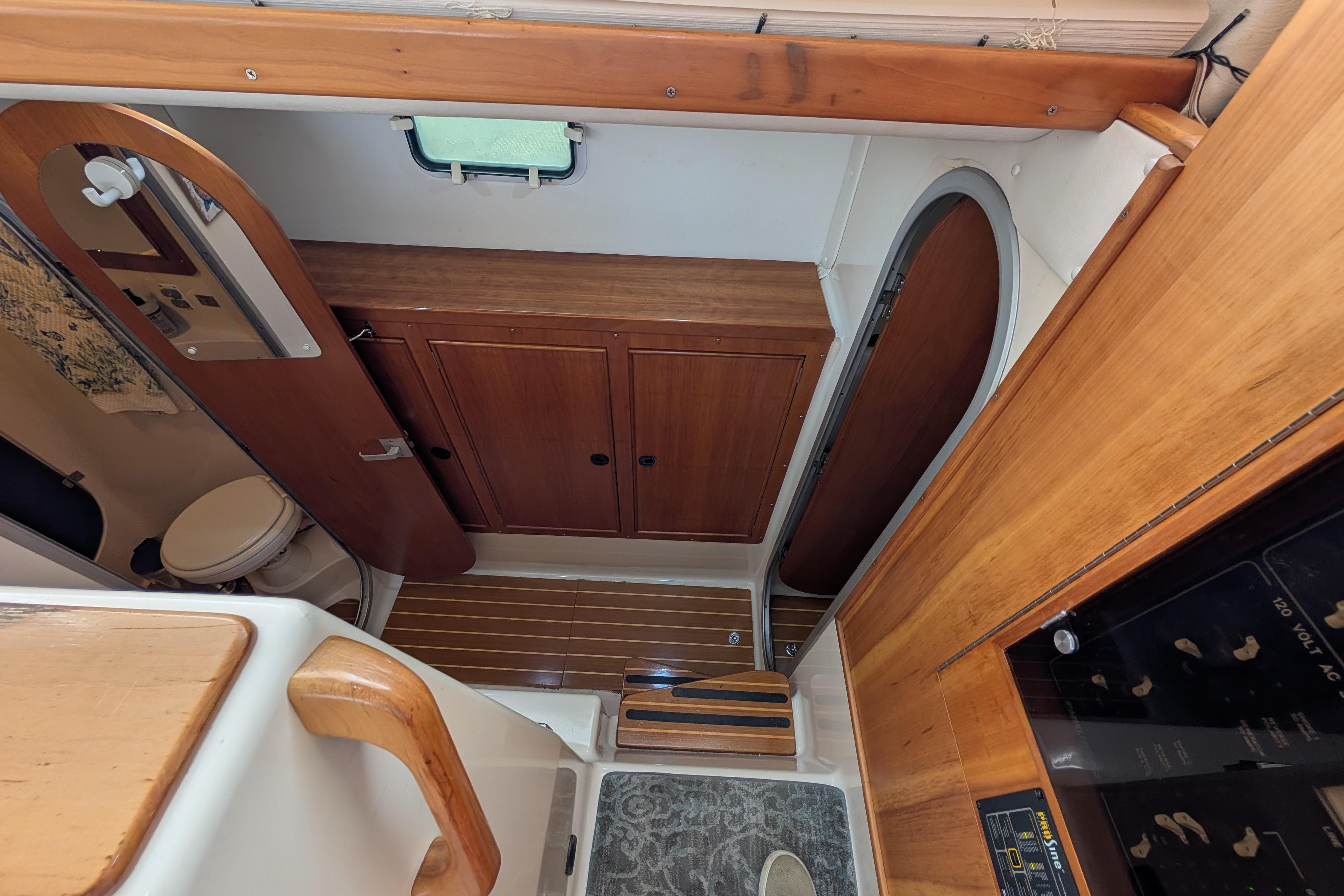 Interior of 2004 PDQ 34 Powercat, featuring wooden cabinetry and compact bathroom.