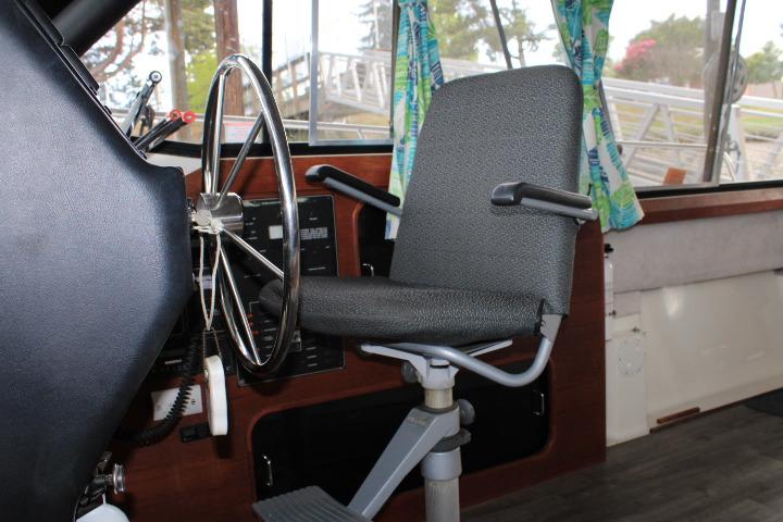 Captain's chair and steering wheel inside 1992 Bayliner 3288 Motoryacht cockpit.