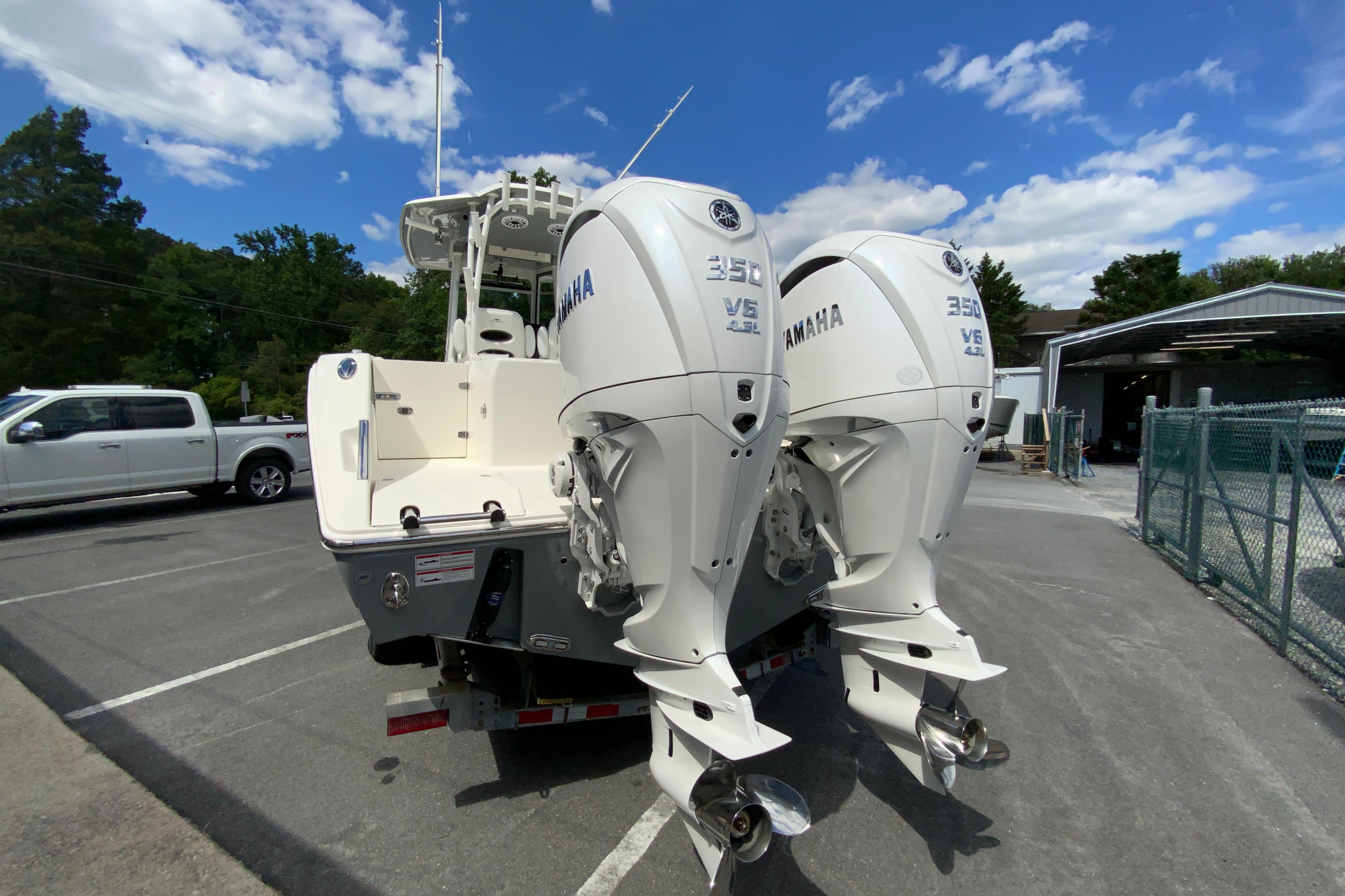 2027 Cobia 320 Center Console with twin Yamaha 350 engines in a parking lot.