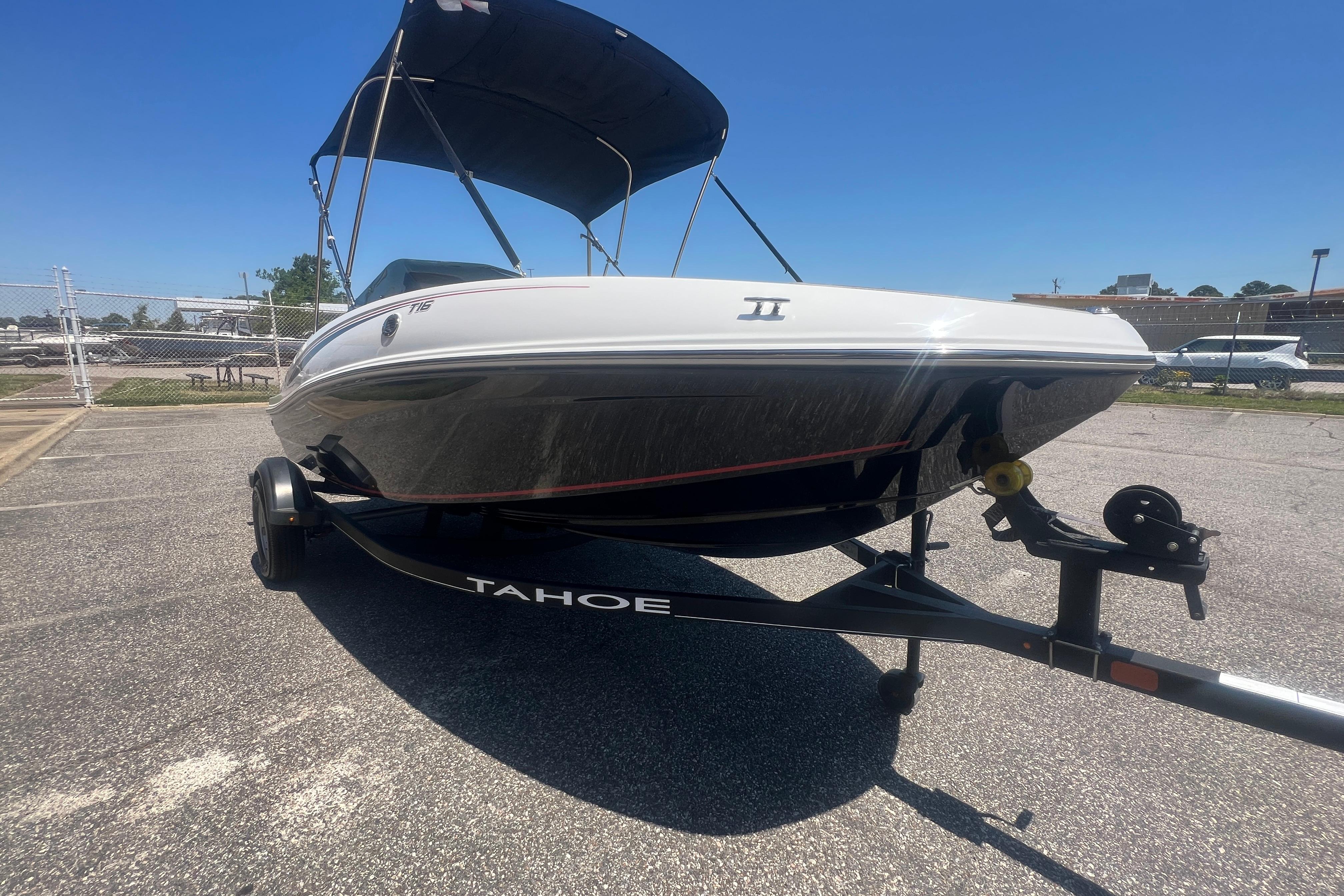 2023 Tahoe T16 boat on trailer, parked outdoors under clear blue sky.