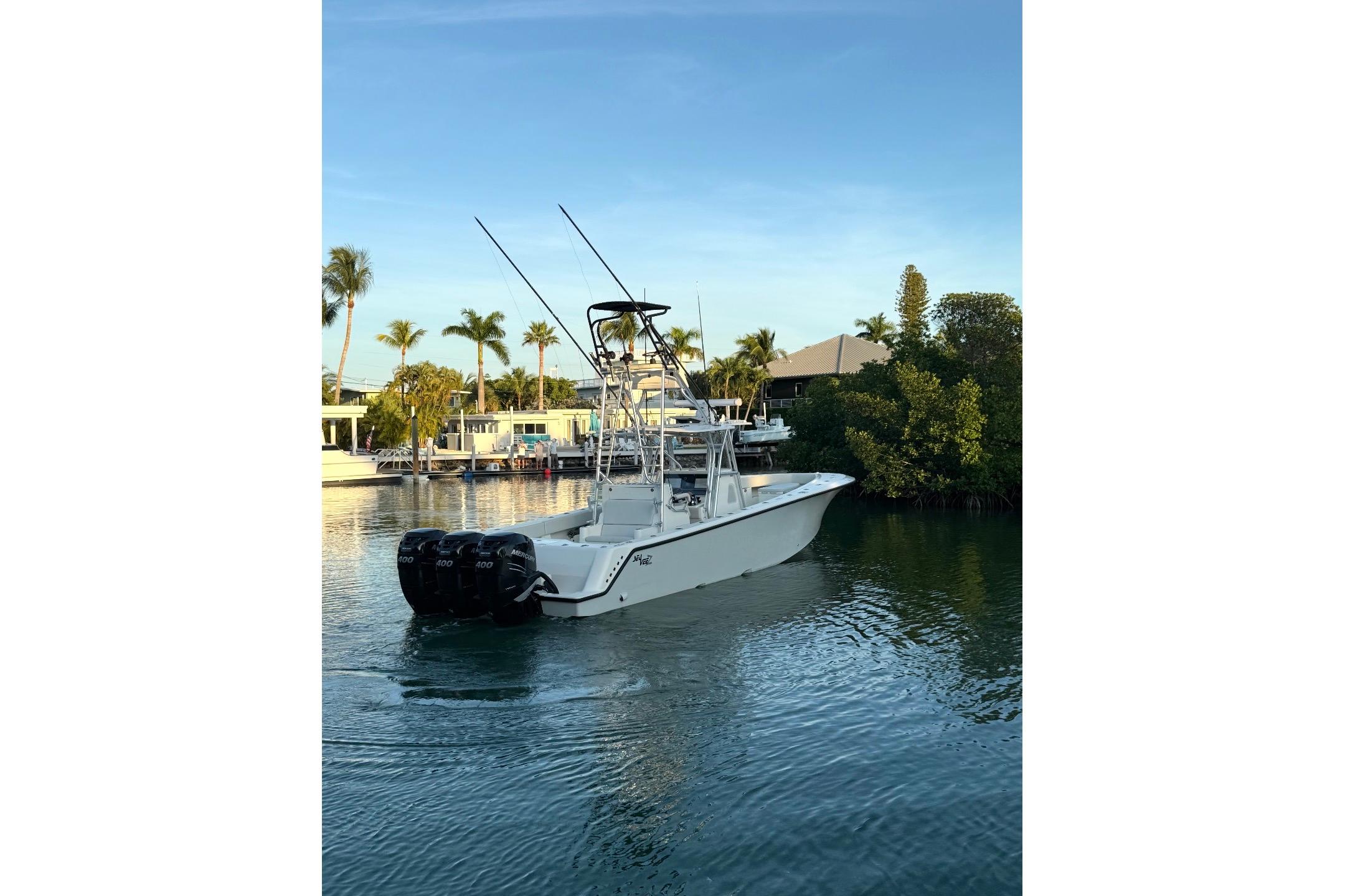 2015 SeaVee 390Z boat with triple engines on a calm waterway, surrounded by palm trees.
