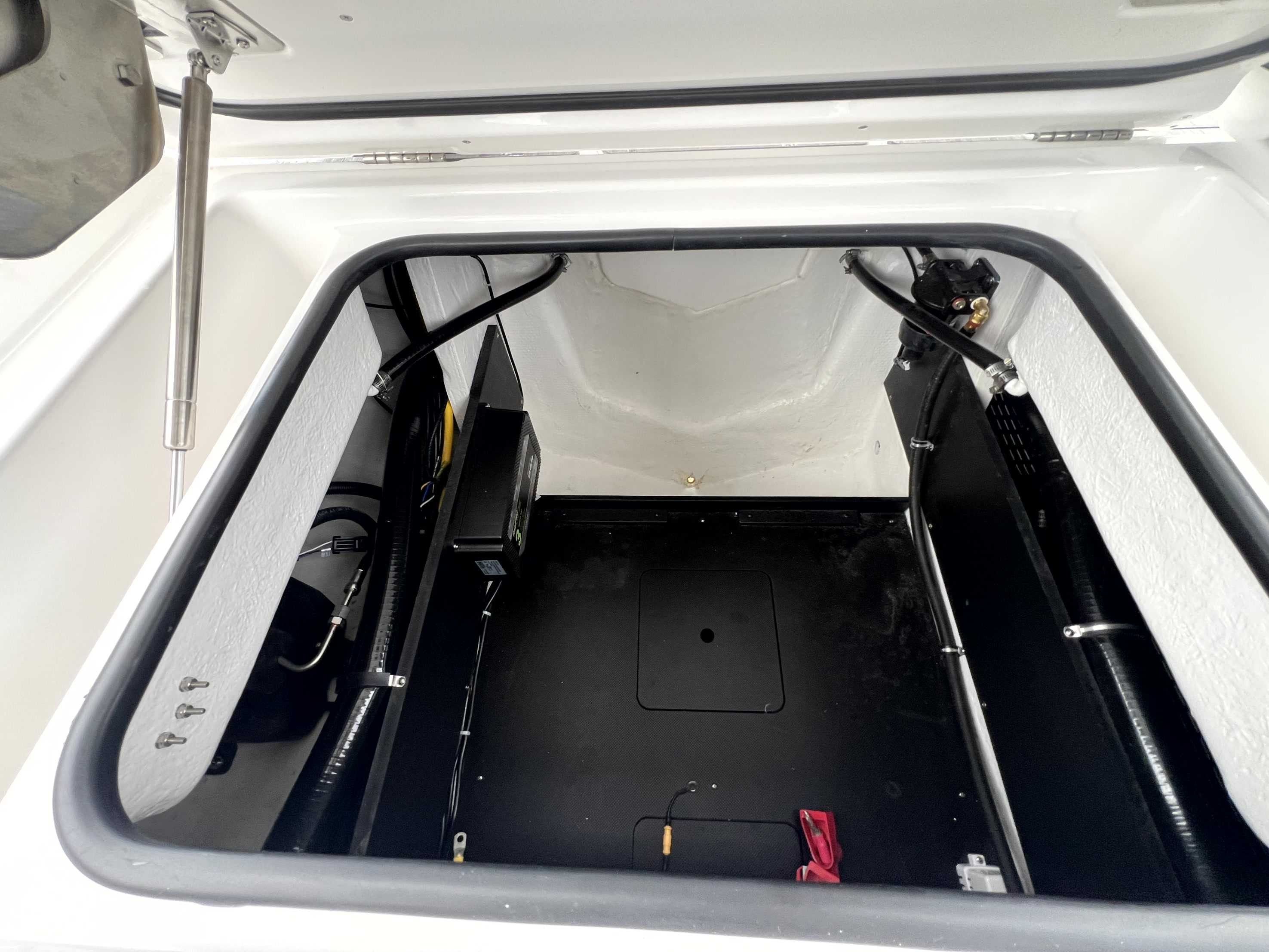 An open storage compartment in the boat with black and white surfaces.