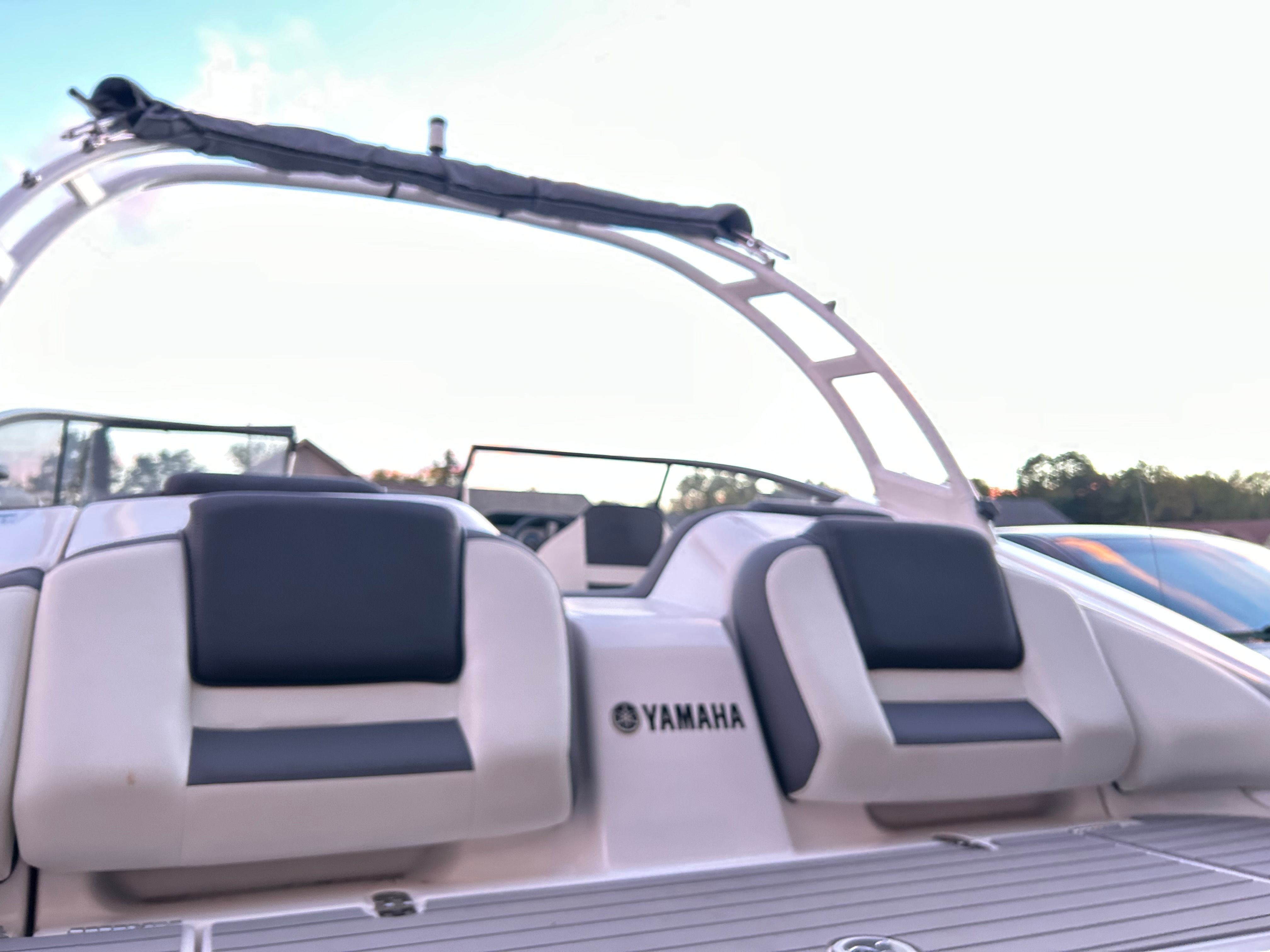 Yamaha AR210 boat with cushioned seats and modern design, parked by the shore.