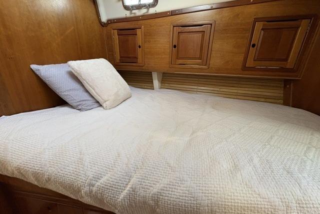 Cozy cabin bed in 2002 Saga 43 yacht with wooden storage cabinets.