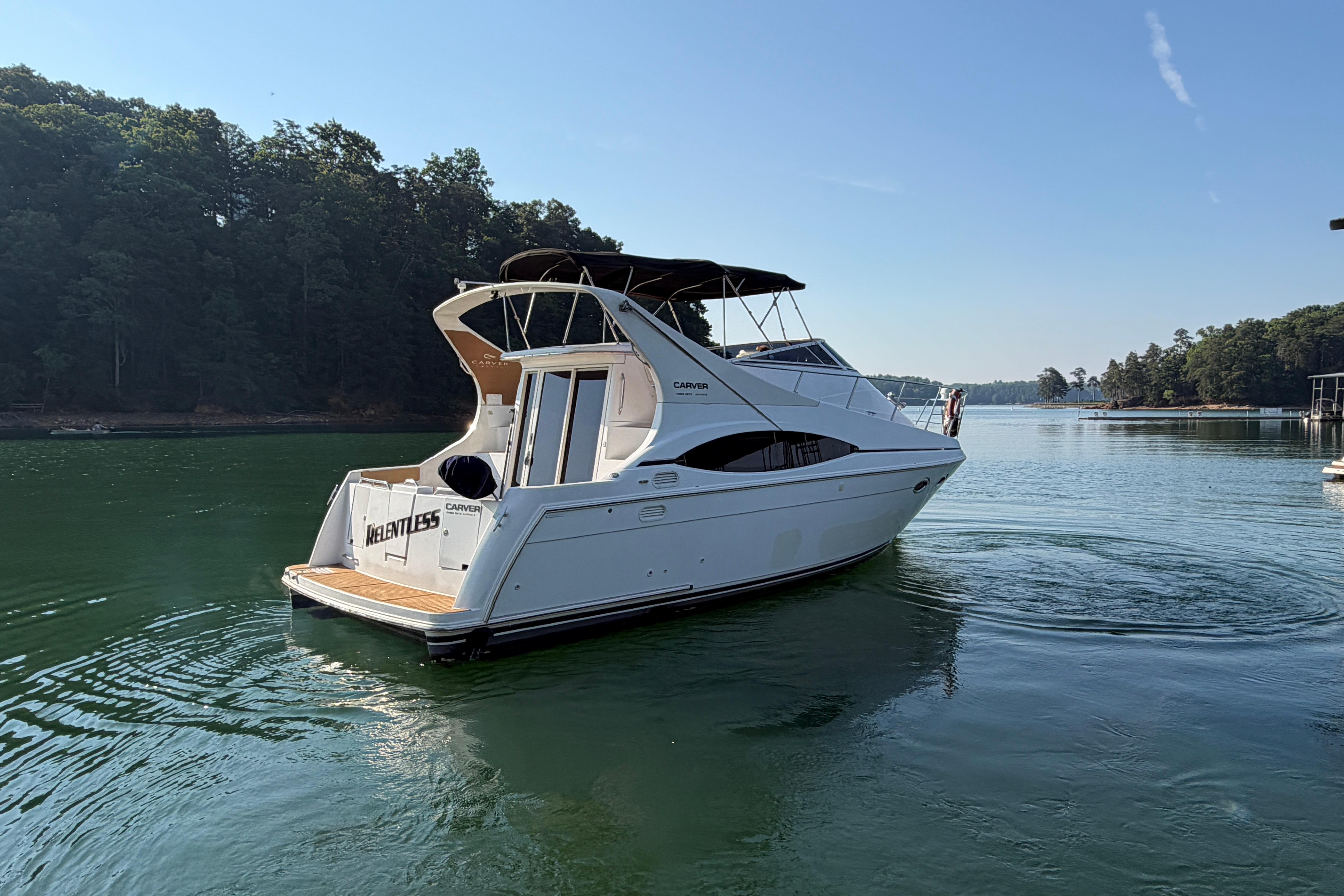 2003 Carver 350 Mariner yacht cruising on a serene lake with forested shoreline.