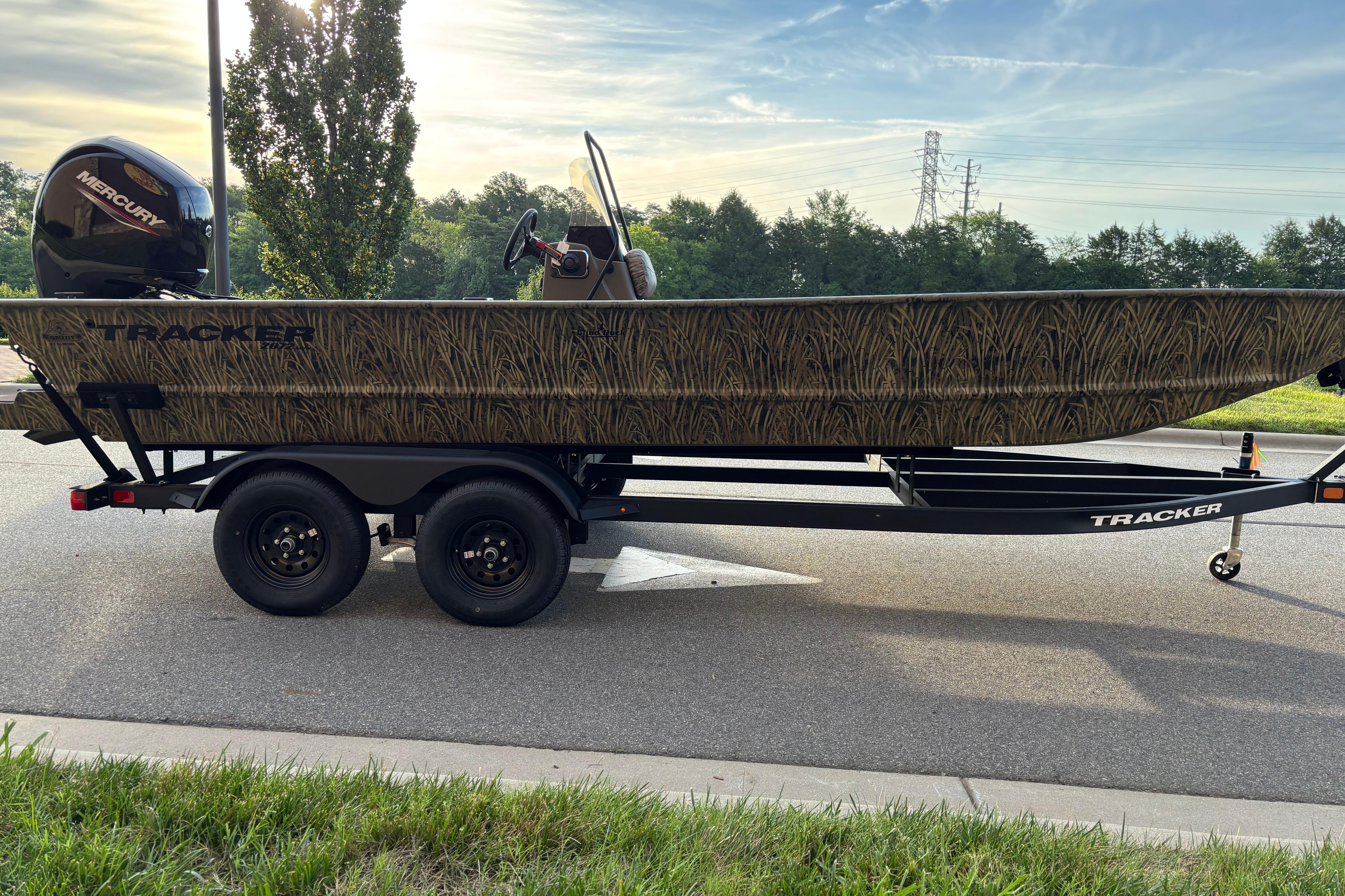 2026 Tracker Grizzly 2072 CC boat on trailer, featuring camouflage design and Mercury engine.