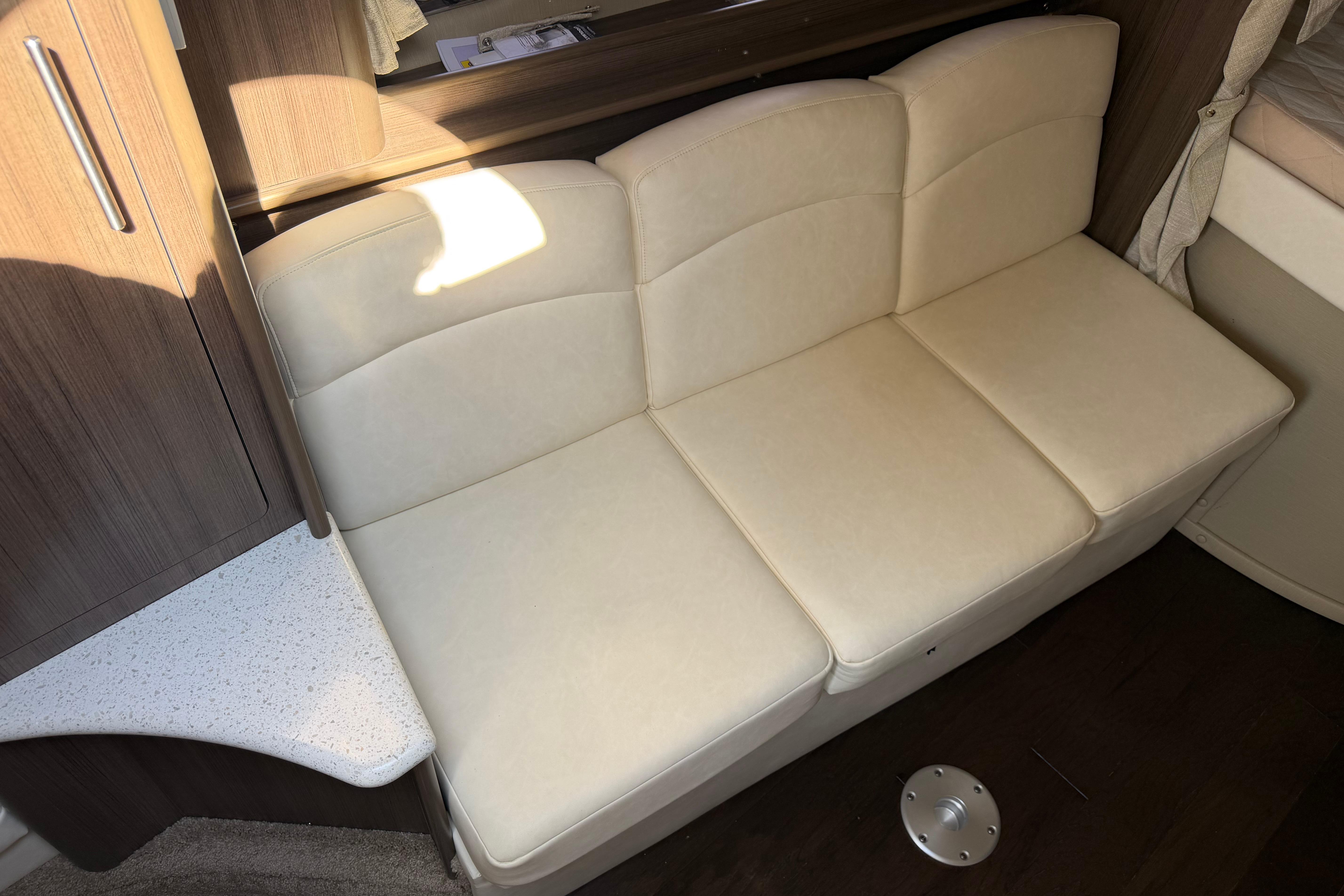 2019 Rinker EX 320 interior with beige leather seating and wooden cabinetry.