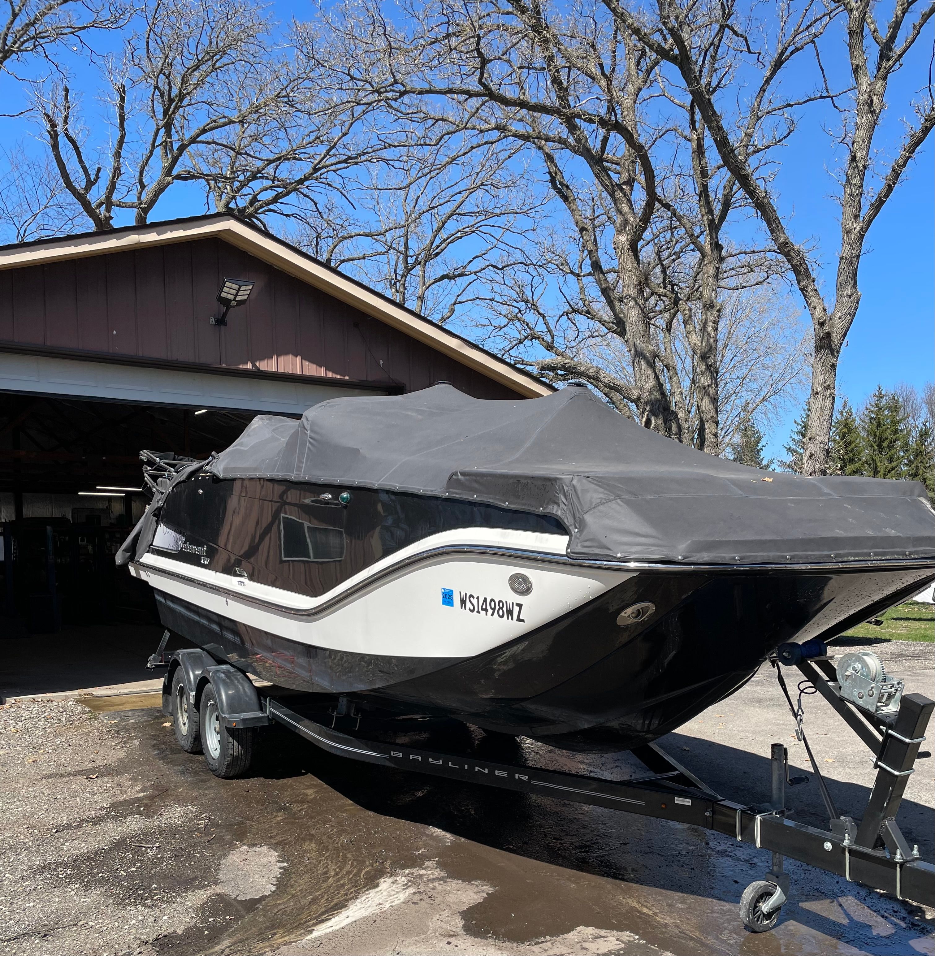 A 2016 Bayliner Element XR7 on a trailer in front of a garage.
