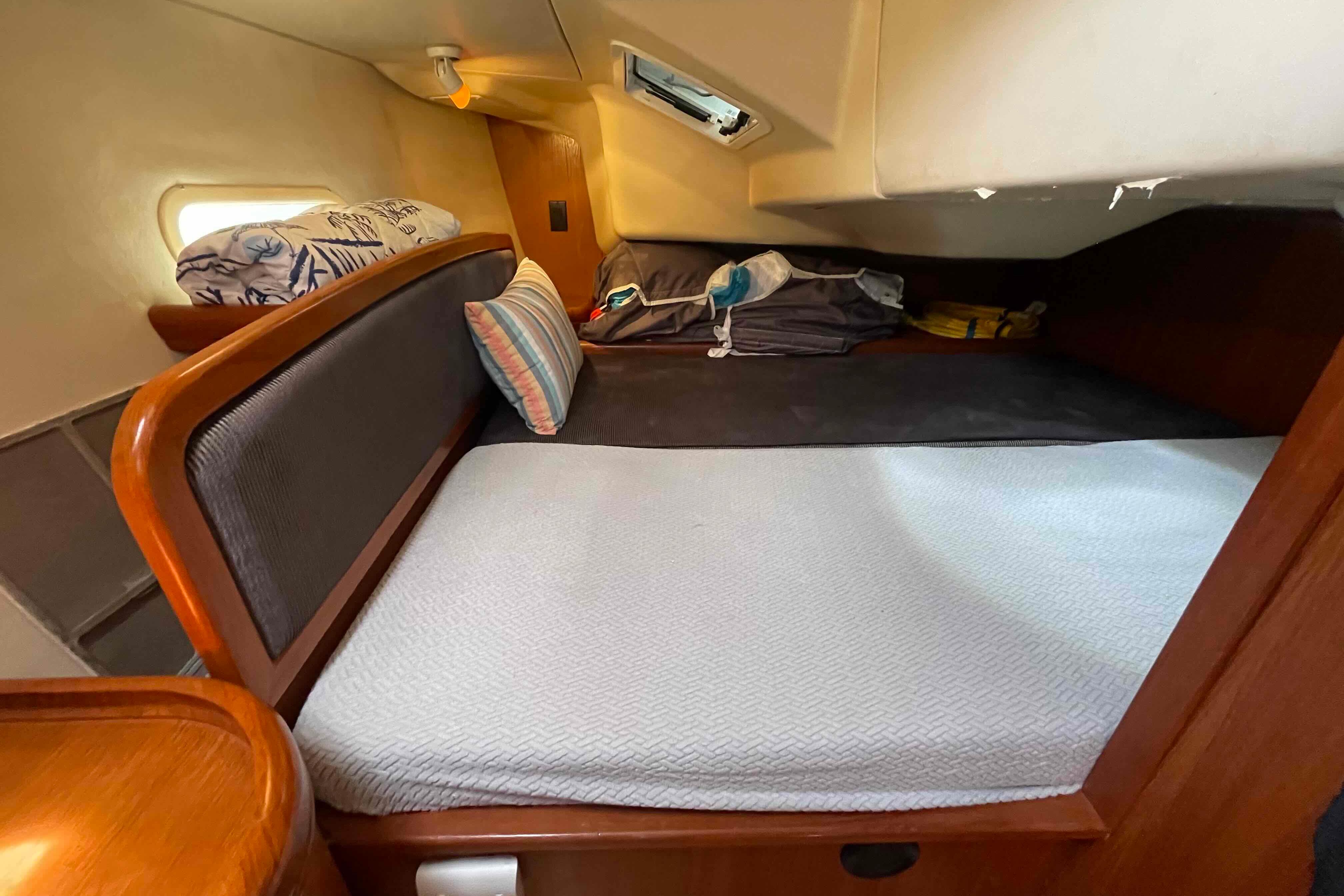 Interior cabin of a 2004 Hunter 36 sailboat with cozy bedding and wooden accents.