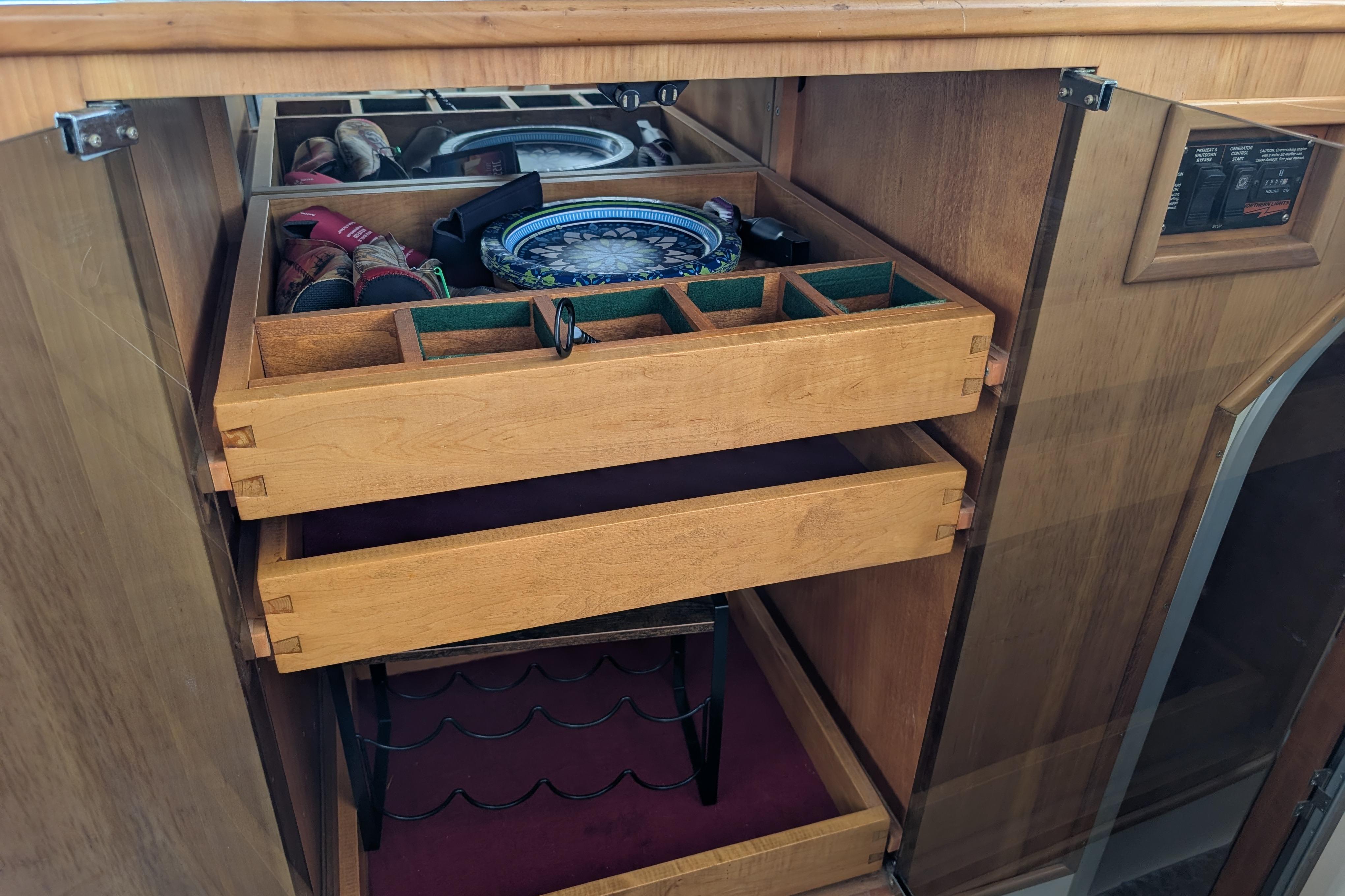 Wooden cabinet with open drawers, displaying organized kitchenware and utensils on a 2004 PDQ 34 Powercat.