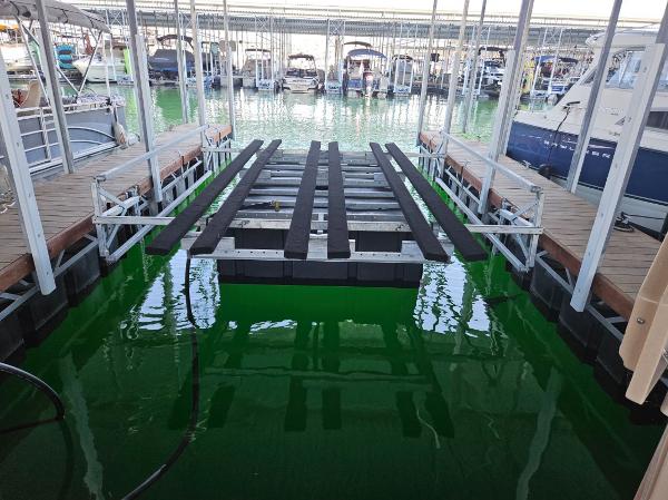 A boat slip in a covered marina with green water.