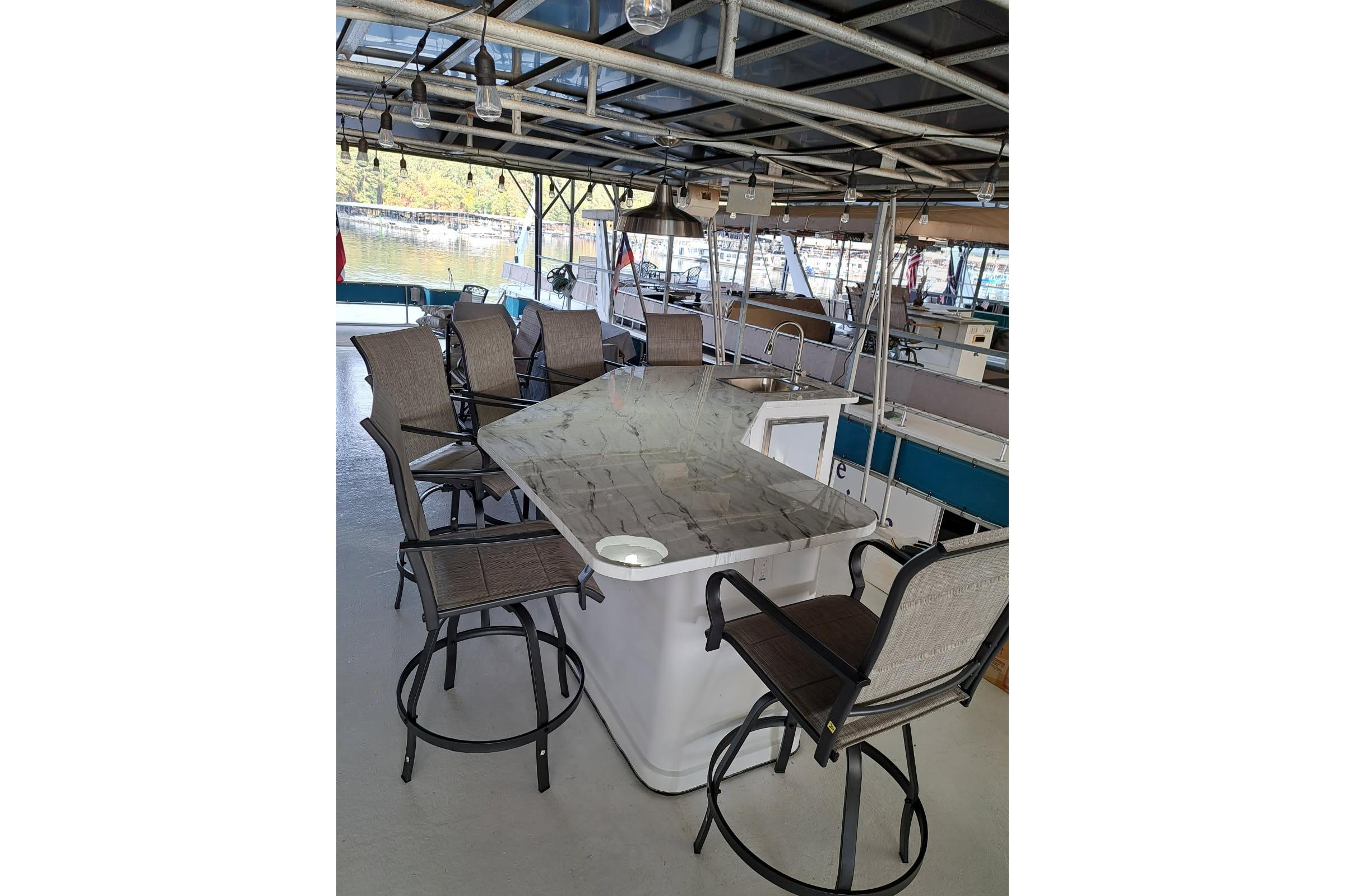 Outdoor seating area on a 1990 Sumerset 16 x 70 houseboat with bar stools and table.