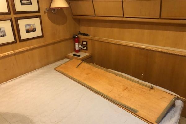 Interior cabin of a 1997 Bertram Convertible yacht with wooden paneling and framed pictures.